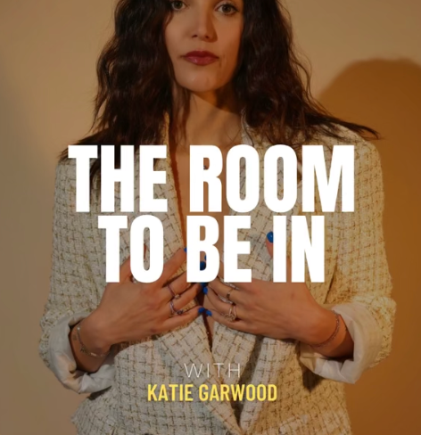 Woman with dark curly hair wearing a beige blazer, hands on chest, with text overlay 'The Room to Be In with Katie Garwood'.