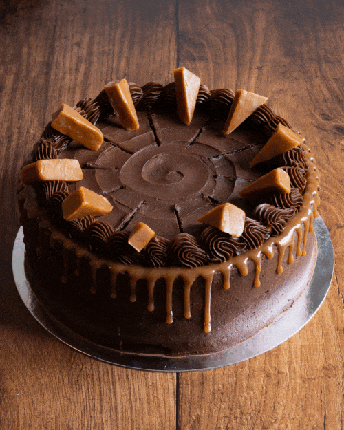 Chocolate cake with caramel pieces and chocolate icing, topped with caramel drizzle around the edges.