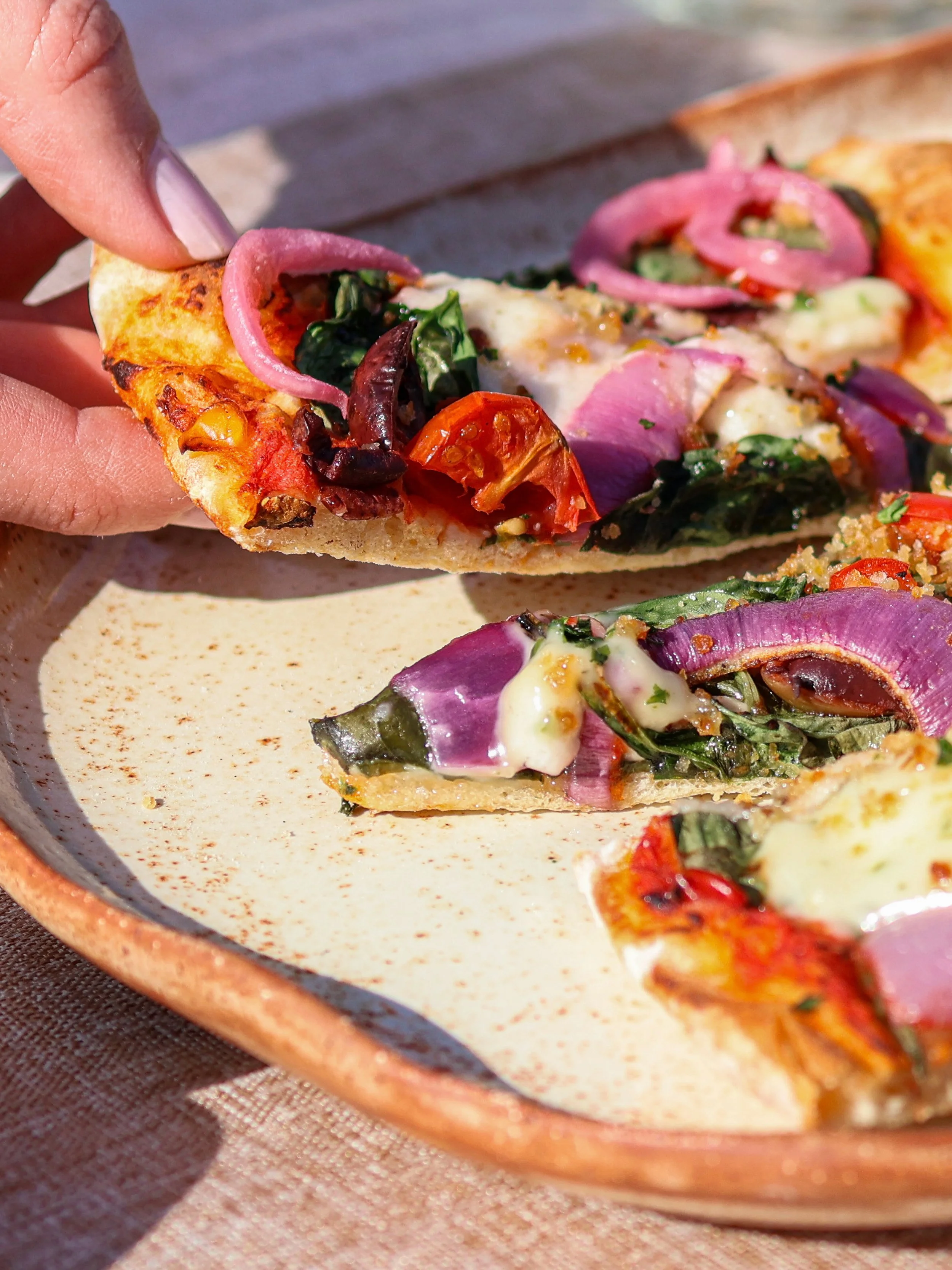 grabbing. aslice of pizza from a ceramic plate