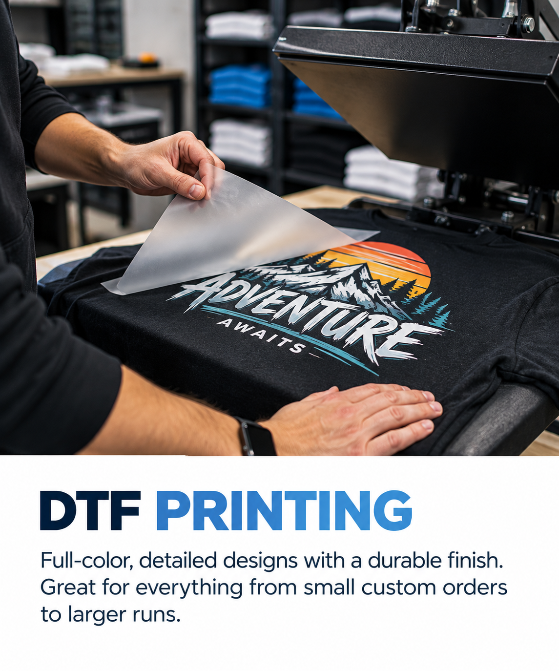 A person applying a full-color heat transfer design of a mountain scene with trees and sunset to a black t-shirt using a heat press machine.