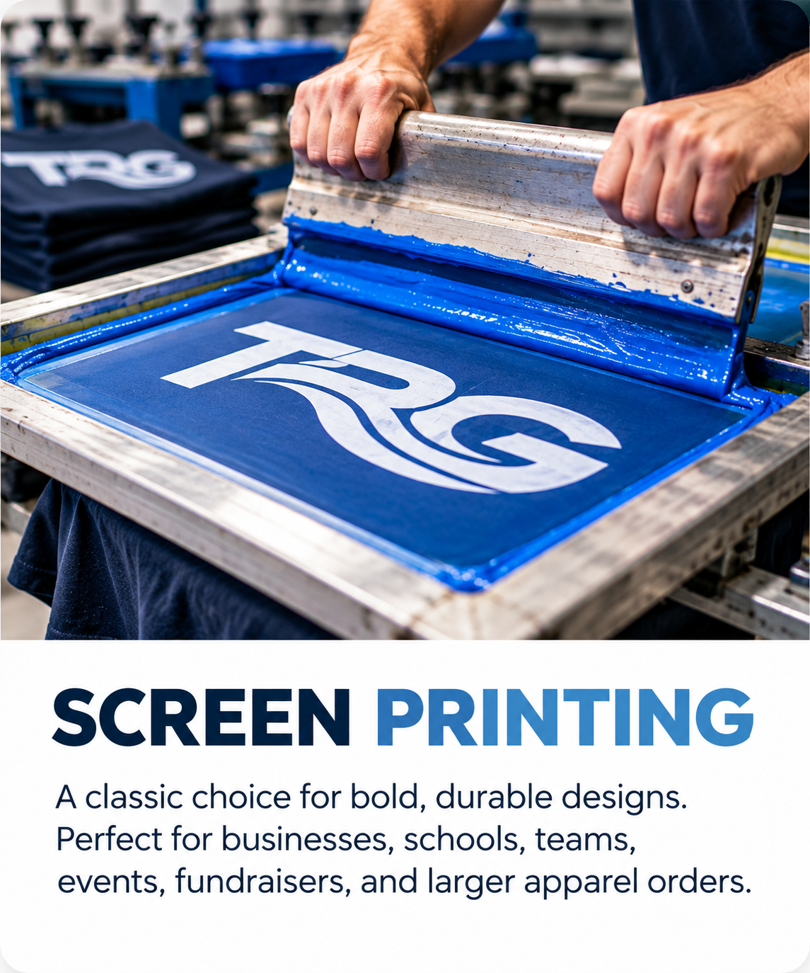 A screen printing process showing a person stamping a blue design with white text onto a fabric. The screen displays the design and the person is using a squeegee to press the ink through the screen.