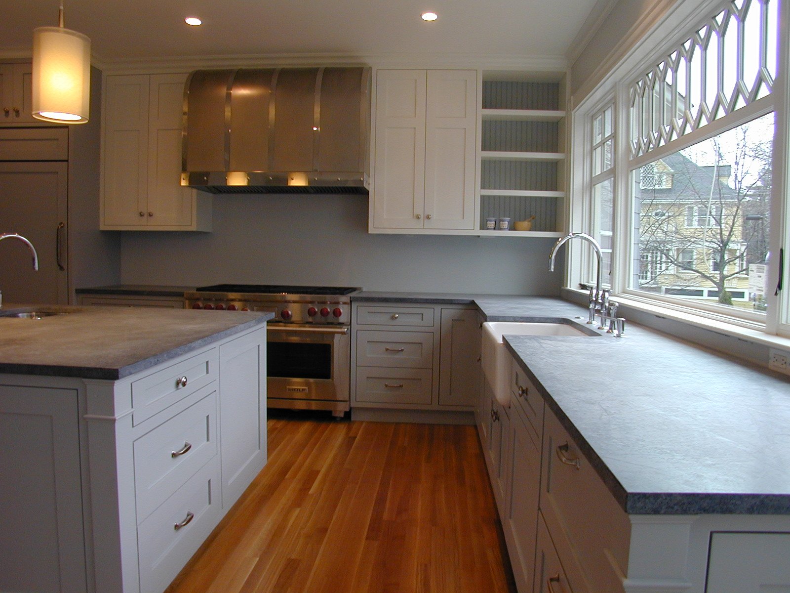 Kitchen with white cabinetry, gray countertops, large windows, and a hardwood floor.