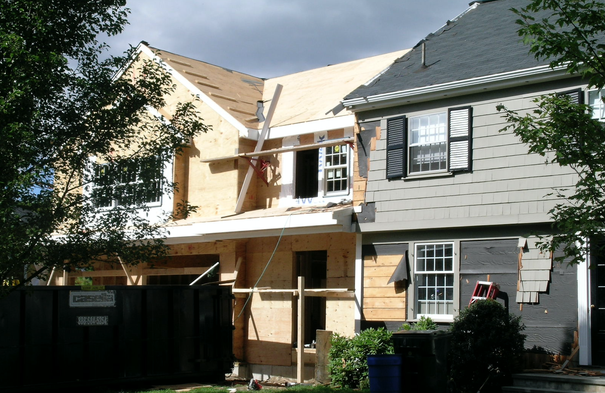House under renovation with exposed plywood, windows, and construction materials.