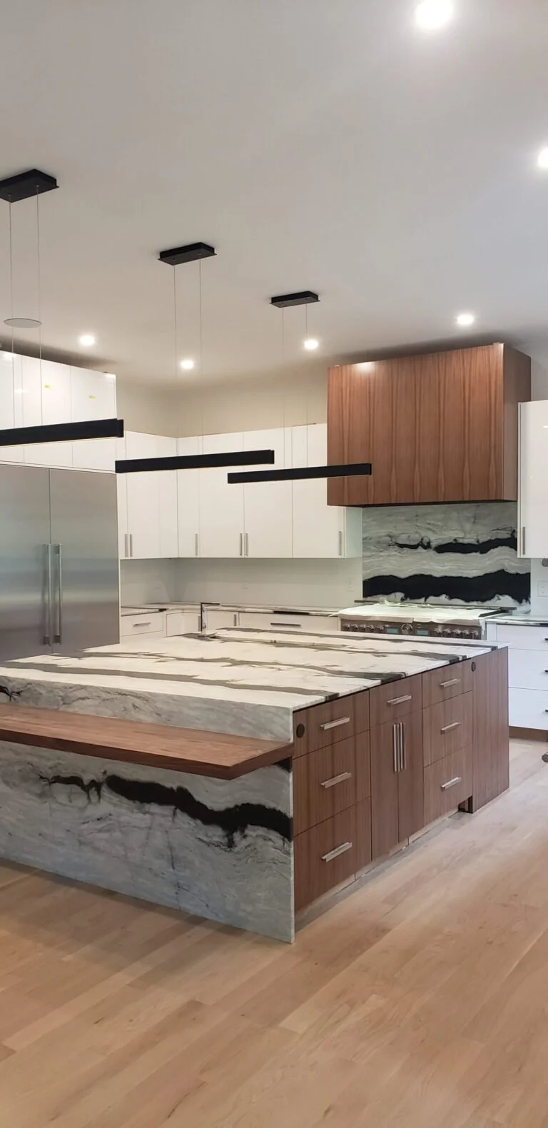 Modern kitchen with white and wooden cabinets, marble countertop, and black accents.