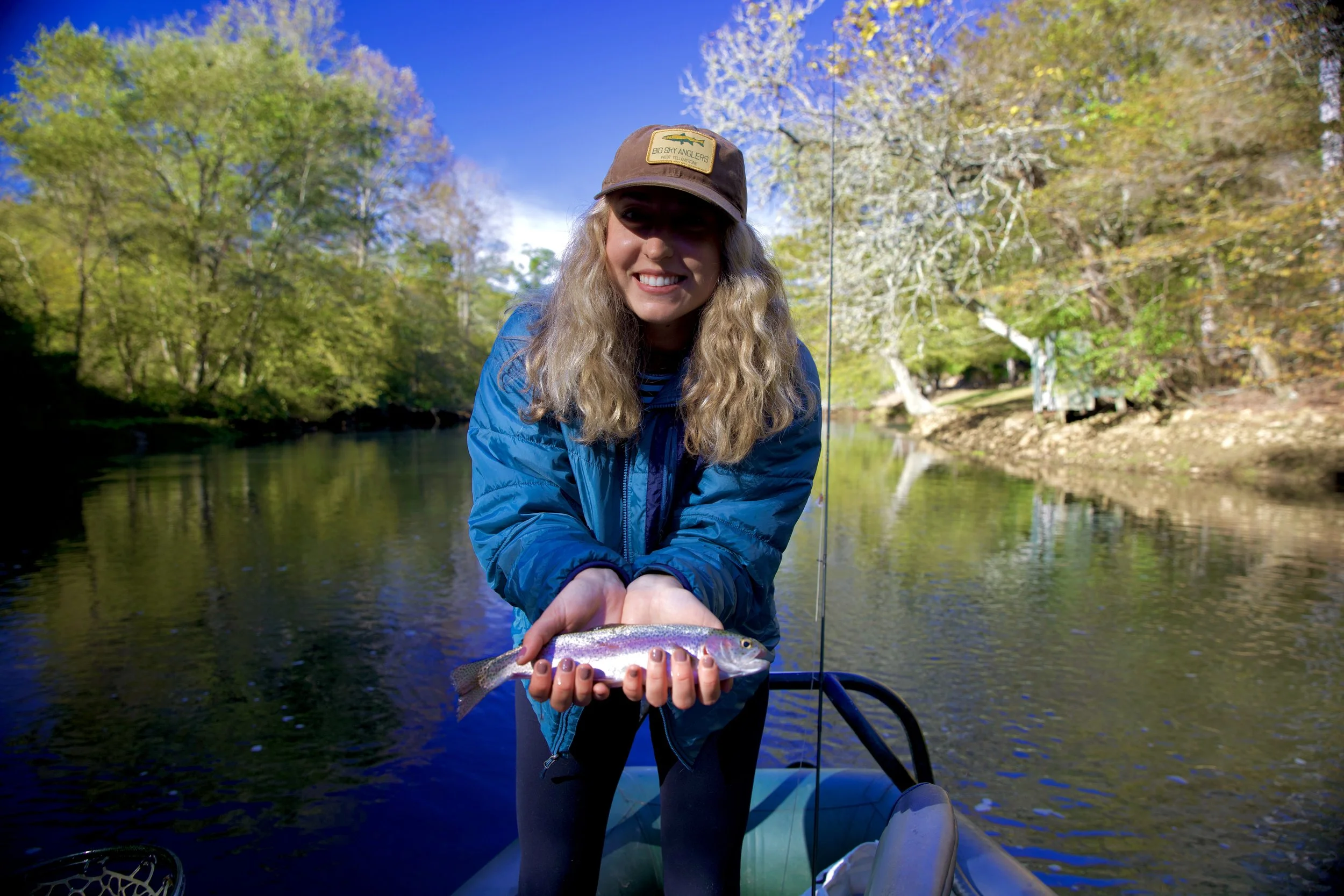 Female angler holding a rainbow trout caught while fly fishing on the Toccoa River near Blue Ridge, Georgia.