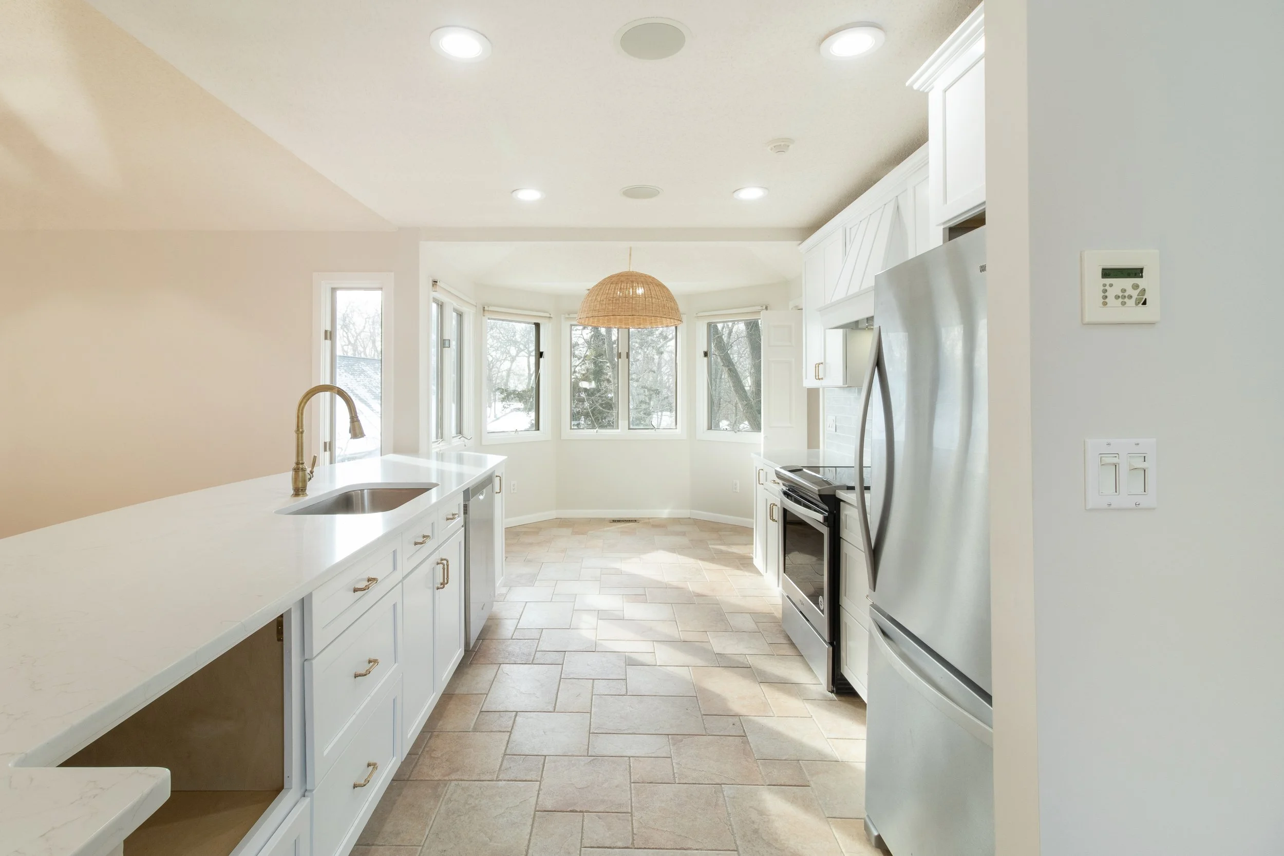 Bright kitchen with large bay window, white cabinets, stainless steel appliances, and tiled floor. Real Estate Photography in East Haven Connecticut