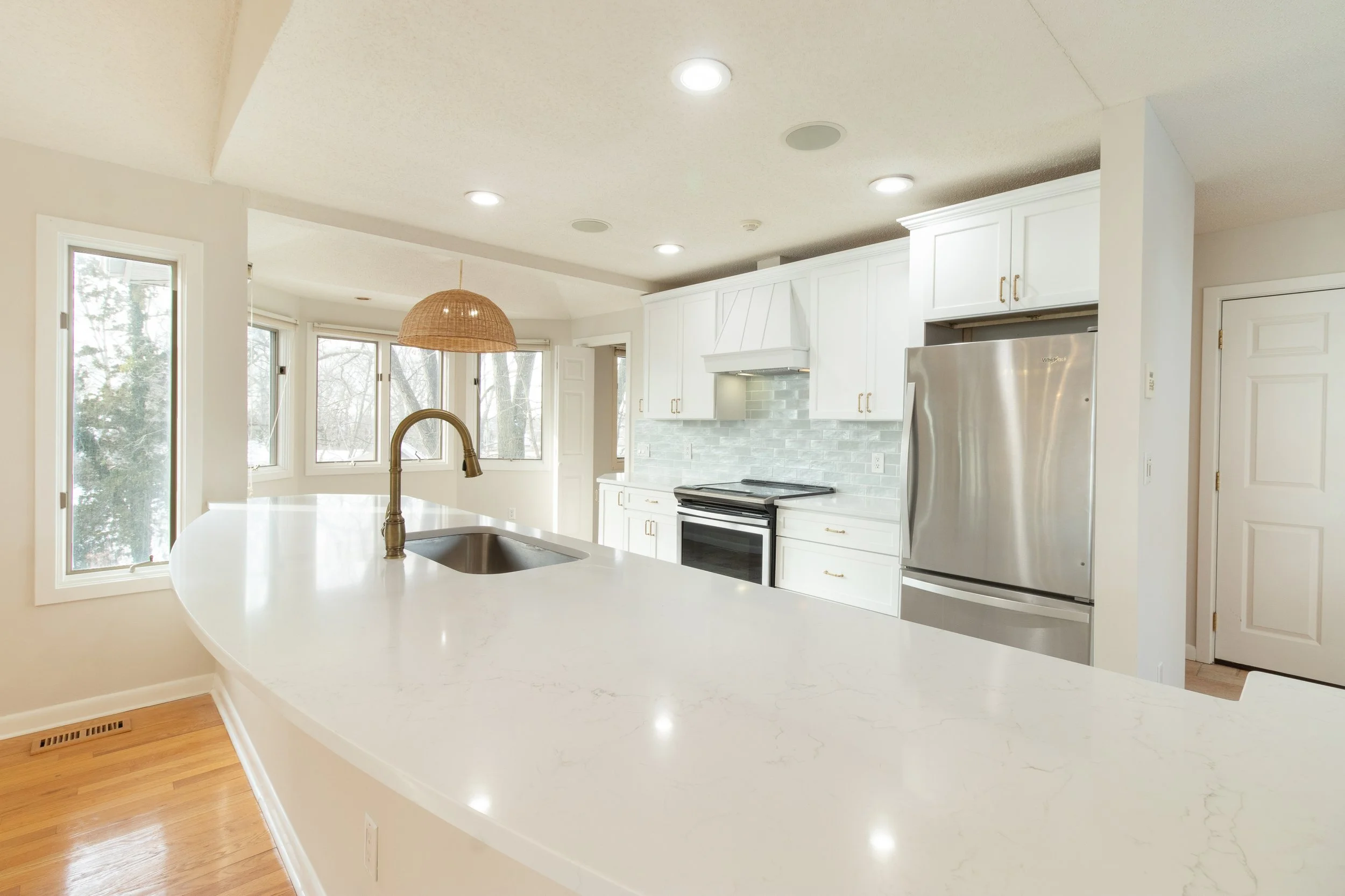 Modern kitchen with white cabinets, stainless steel refrigerator, and a large white marble island.