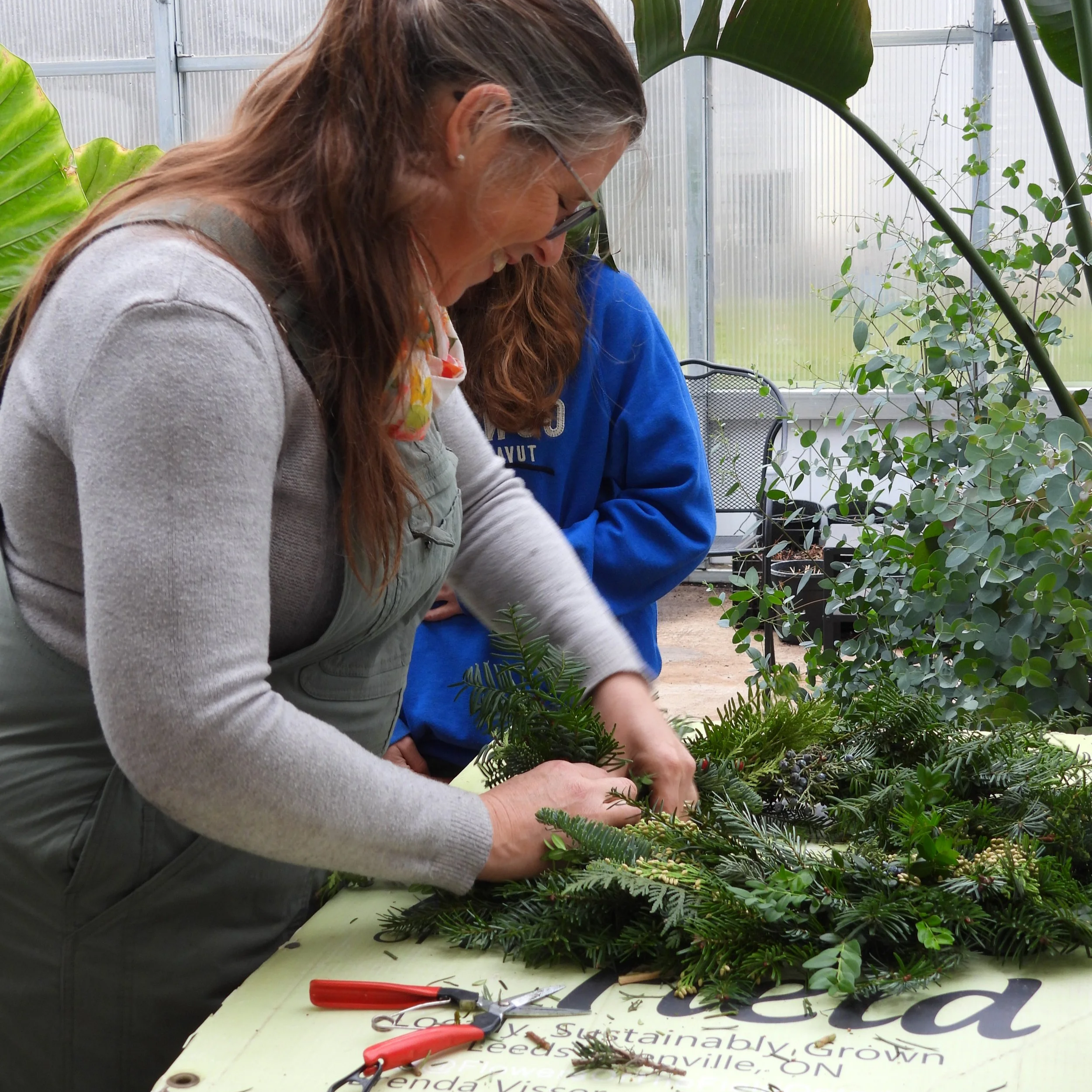 Brenda creating Christmas wreath in greenhouse