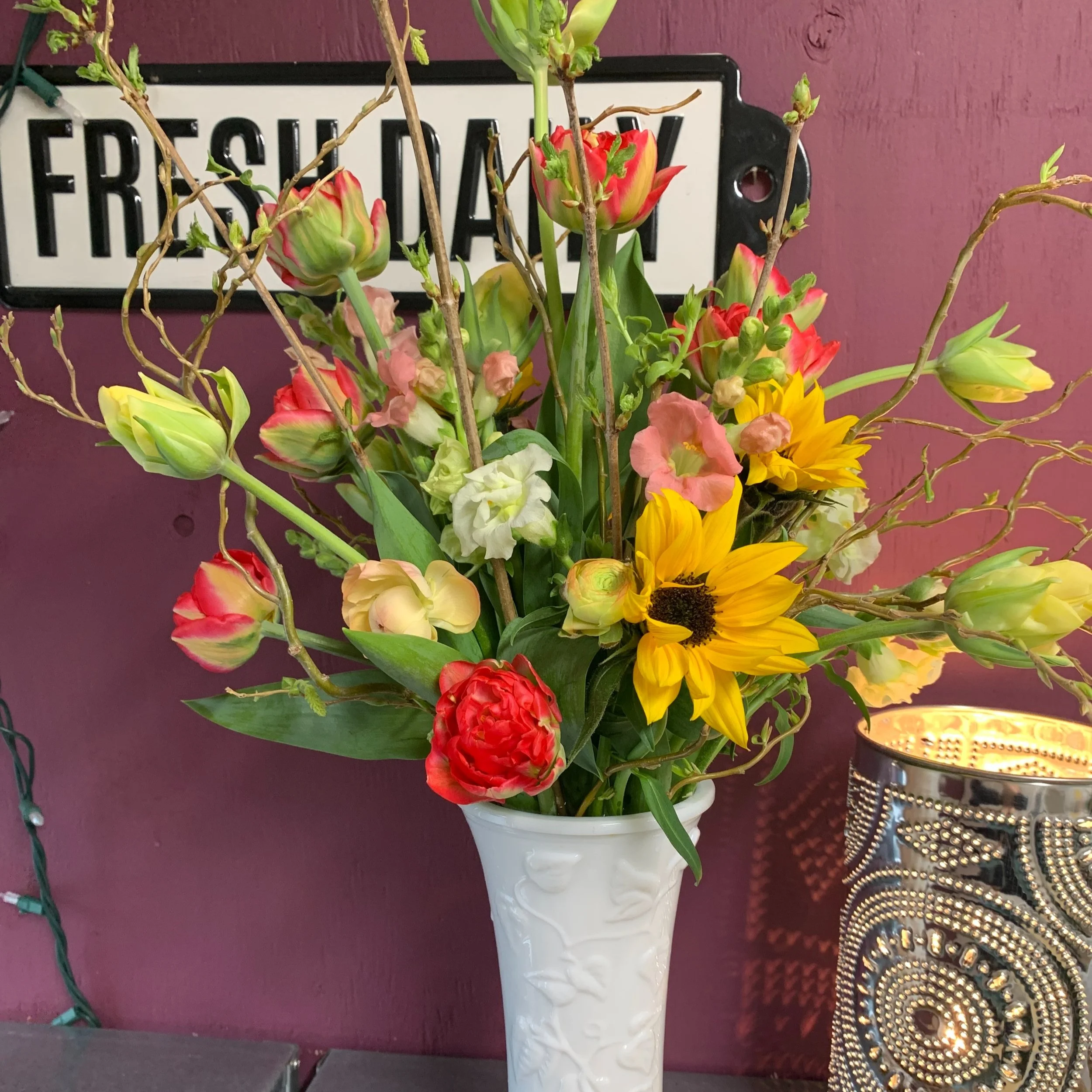 Arrangement in milk glass with tulips branches and spring flowers