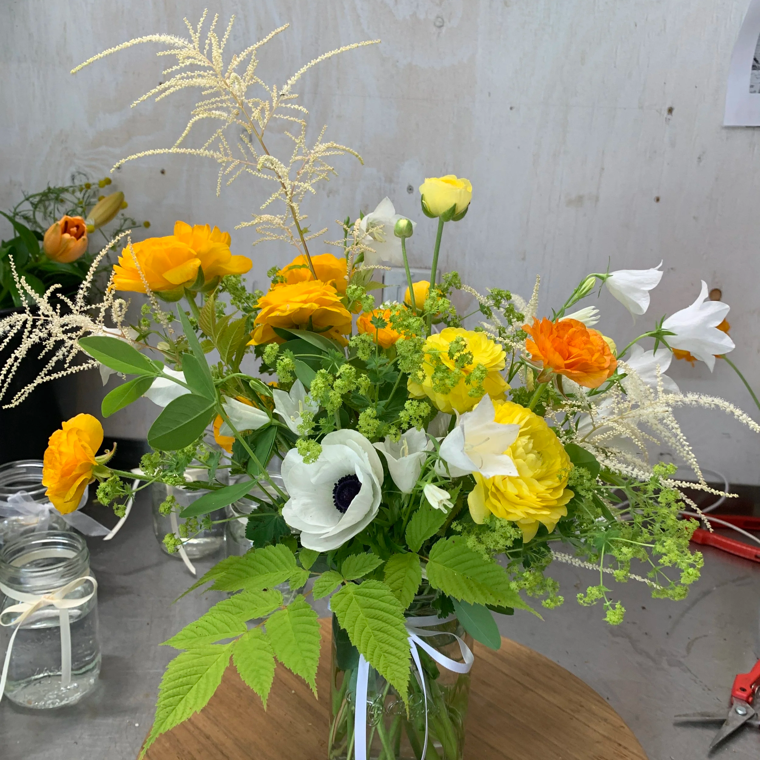 golden, butter yellow, and white flowers with chartreuse greens for spring using our farm grown fresh flowers  from Flowers of the Field in a green glass vase