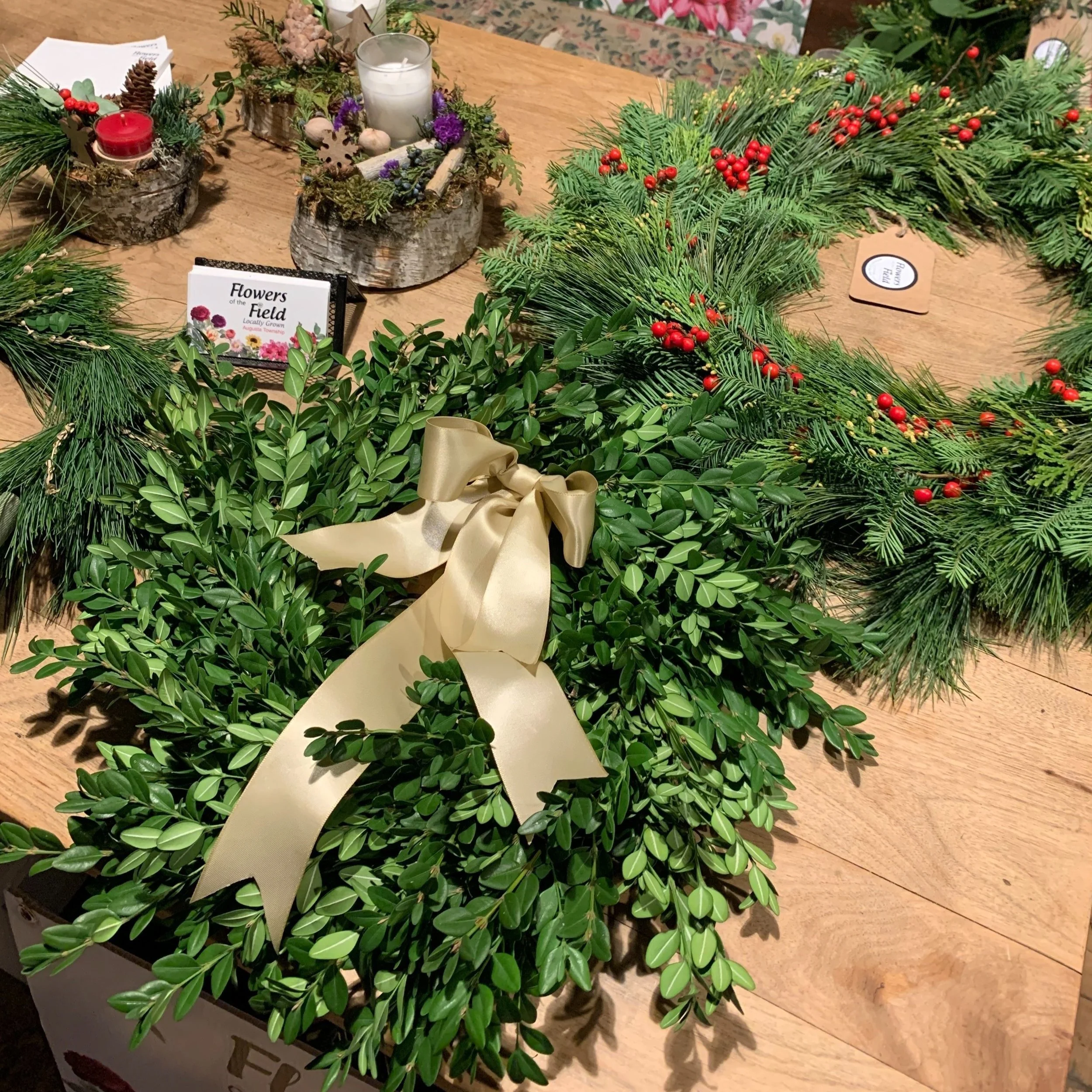 fresh boxwood cedar wreath beside wreath made of yew, cedar and pine