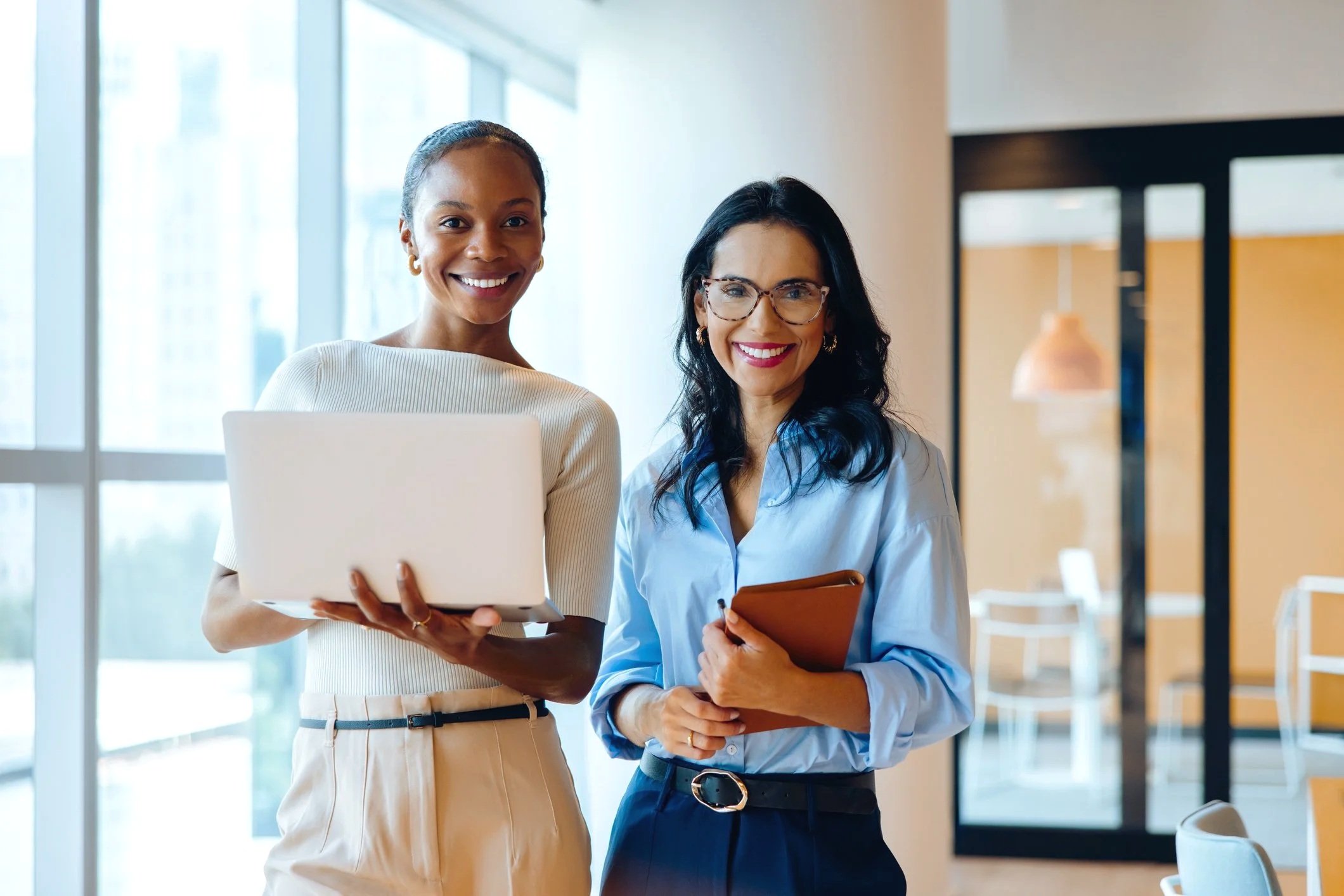 Two recruiting professionals standing together in a bright open office.
