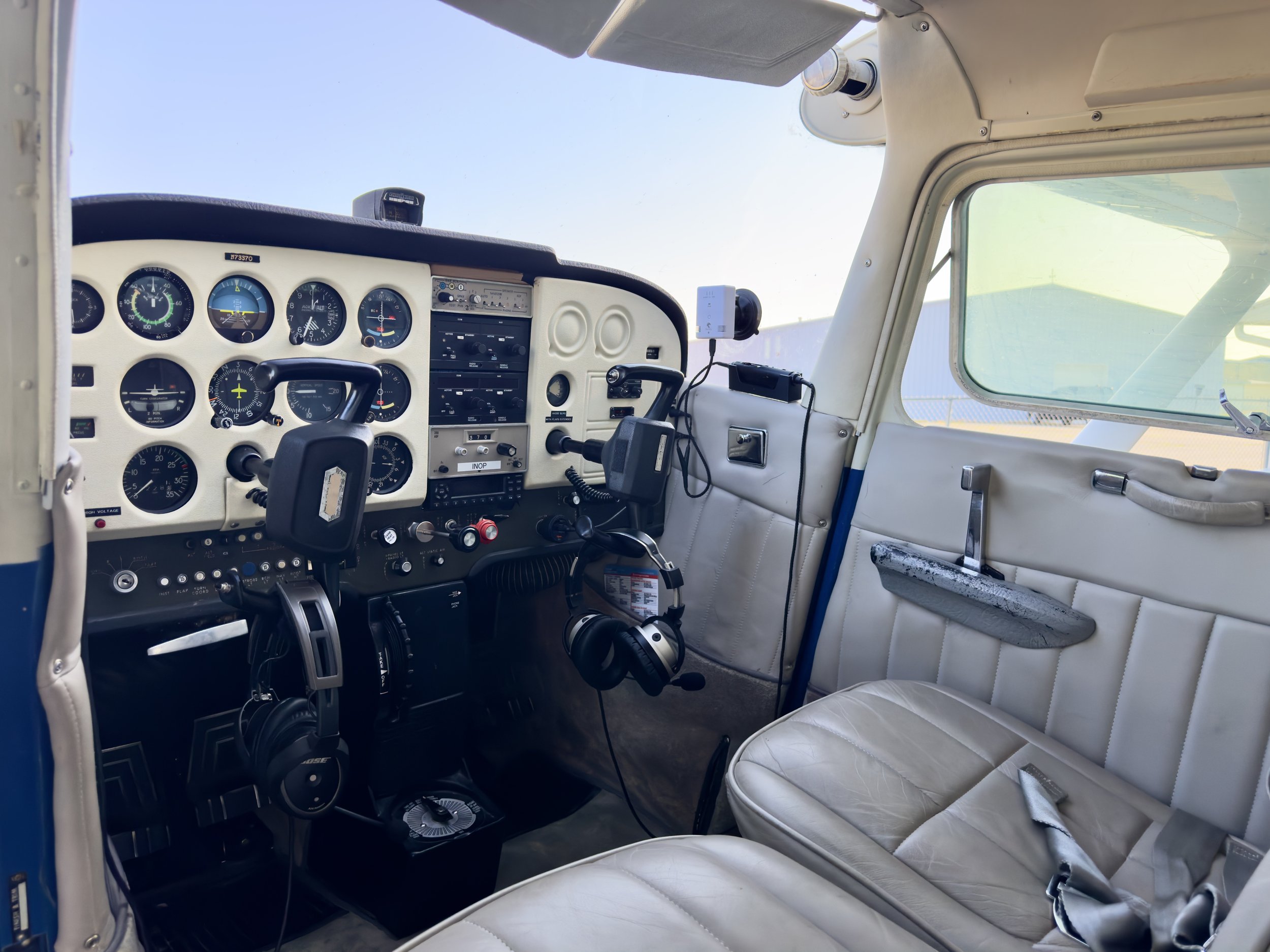 Interior cockpit of a small airplane with various gauges, a steering wheel, a radio, and a seat with a headrest.