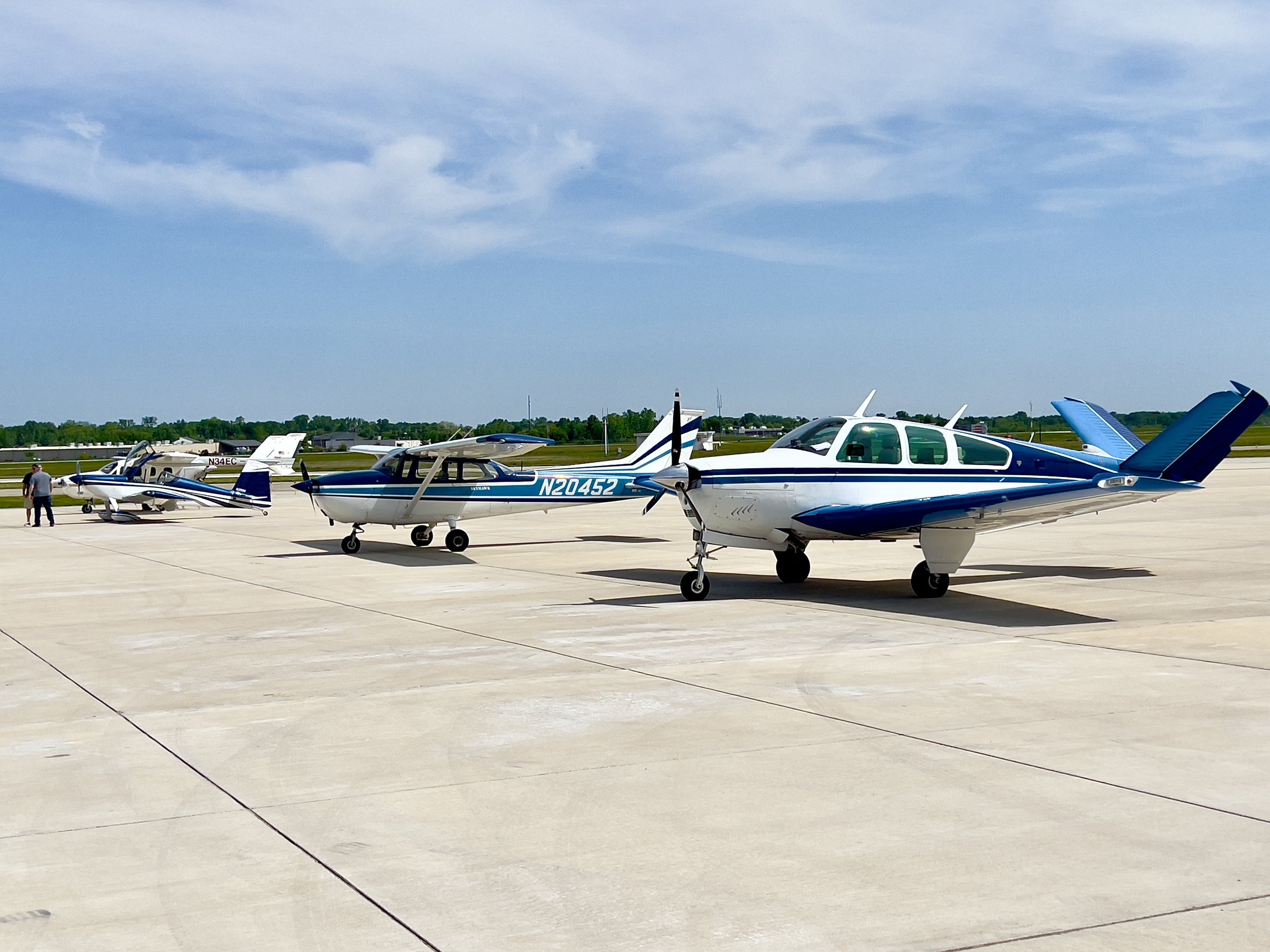 Small private planes parked on an airport tarmac under a partly cloudy sky.