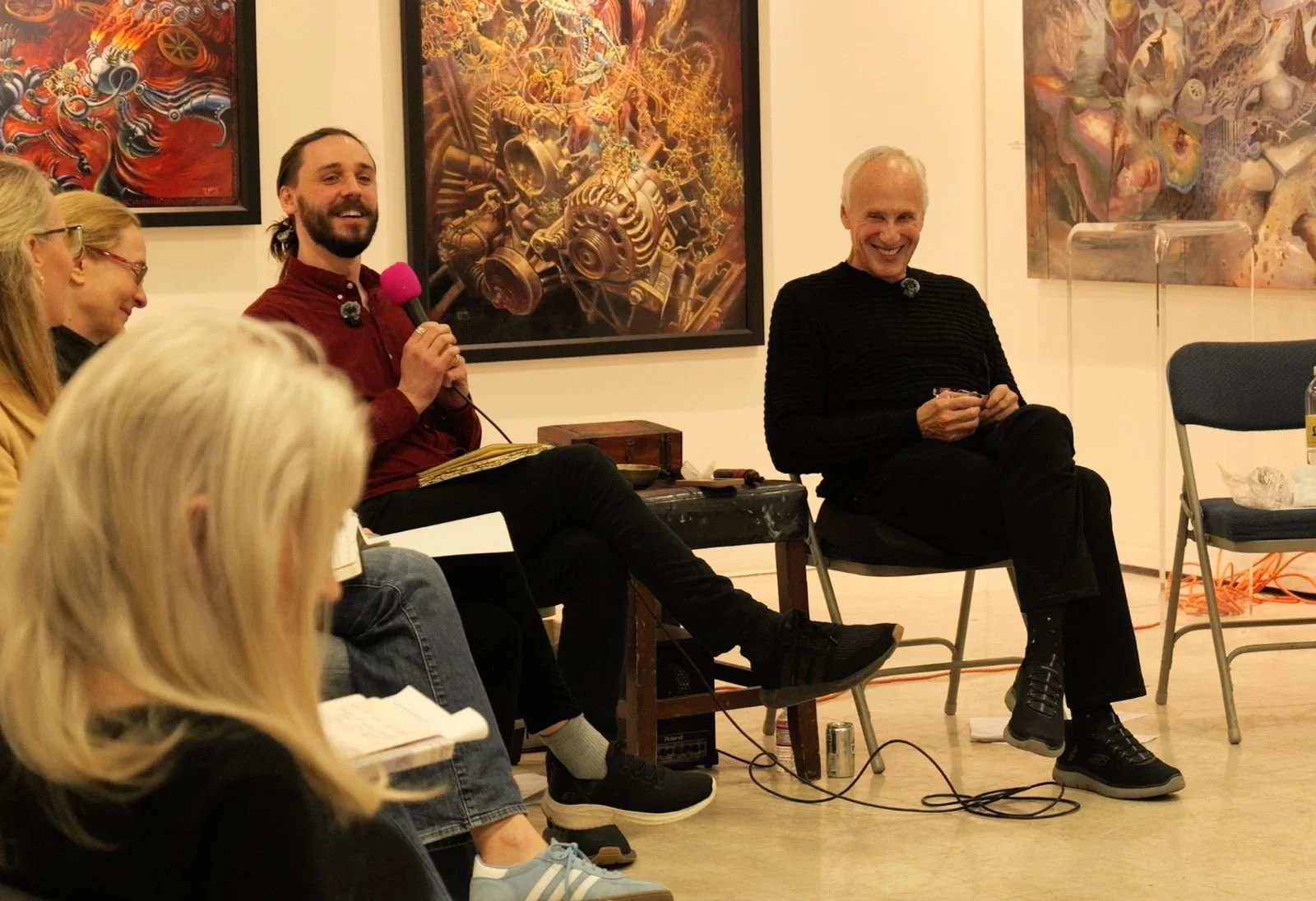 Malibu Poet Laureate Nathan Hassall and Neuroscience Researcher and Best-selling Author, Mark Waldman, pictured at a live workshop. People sitting and chatting at an art gallery, with colorful abstract paintings on the wall behind them.