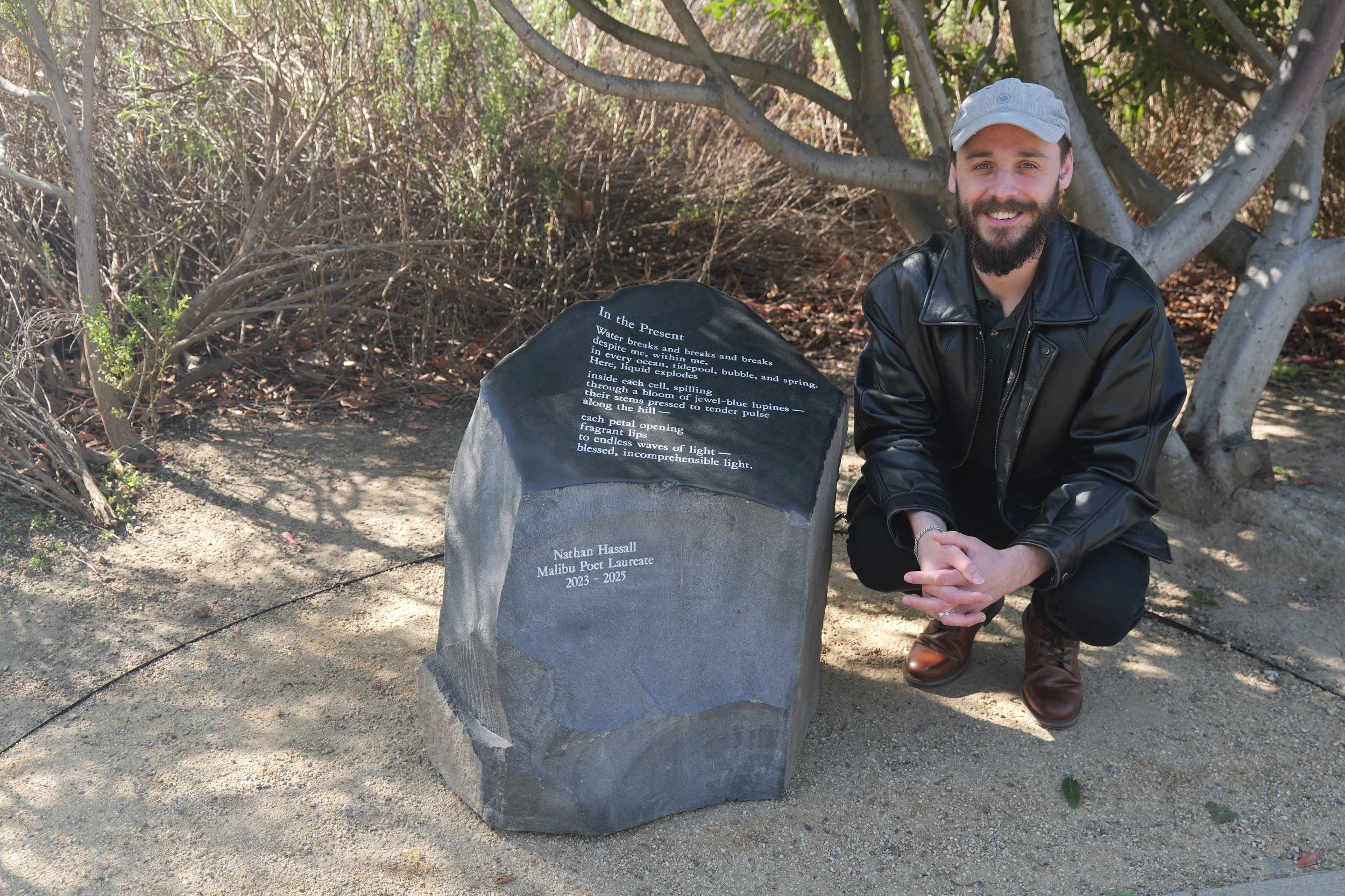 Photo of Malibu Poet Laureate, Nathan Hassall, and his poetry stone inscribed with his poem titled, "In the Present"