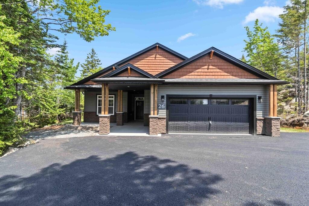 Modern single-story house with two-car garage, surrounded by trees.