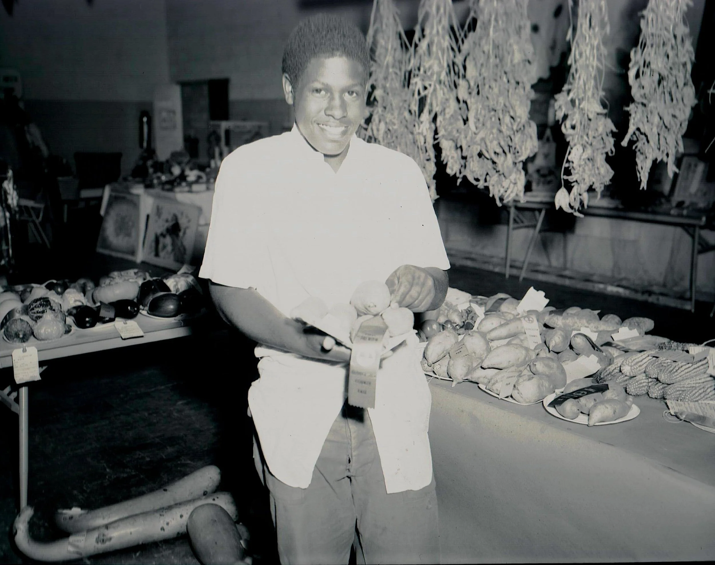Ronald Davis displays a ribbon alongside yams at a 4-H fair.