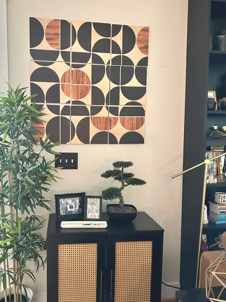 AFTER: This cabinet is black to match the bookshelves, but has rattan inserts in the doors and midcentury legs--coupled with an MCM tiled artwork on the wall, these two pieces help the eye transition from the dark library atmosphere to the foyer/entr