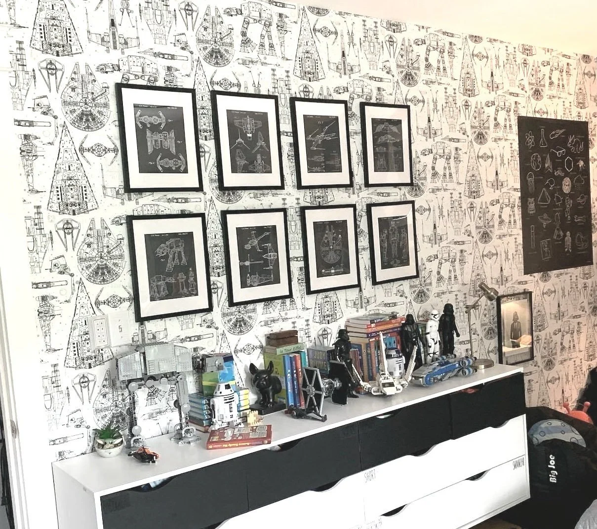 AFTER (turned 7yo's Star Wars room): a better view of the feature wall. Schematic Star Wars vehicle drawings, with an eight-frame gallery wall of MORE schematic drawings. Is the dresser top cluttered and are there books on the floor? Yes. Because a c