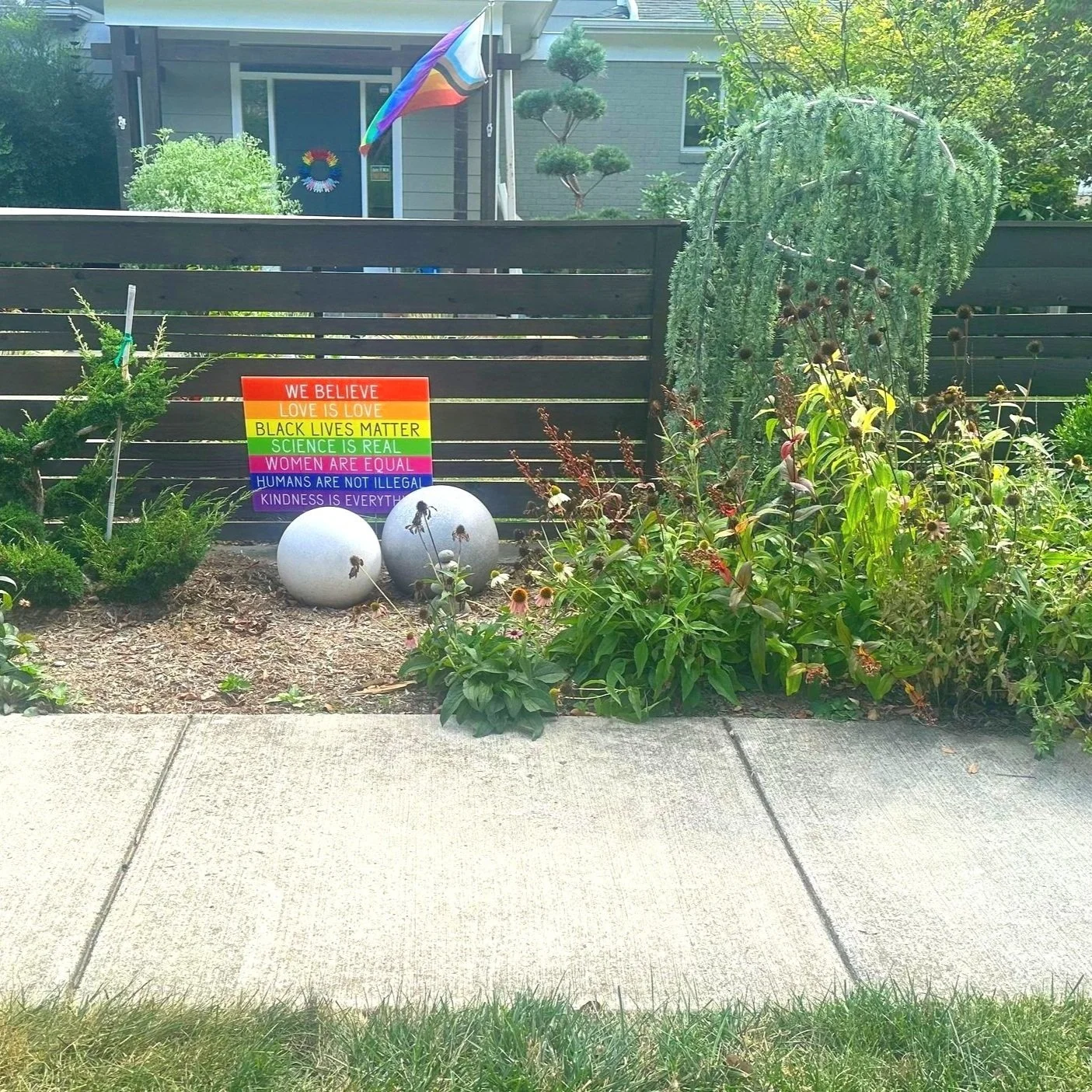 AFTER: a horizontal midcentury cedar fence delineates and defines the yard, bisecting the "private pollinator garden" on the inside from the public facing ornamental shrubs on the exterior. 