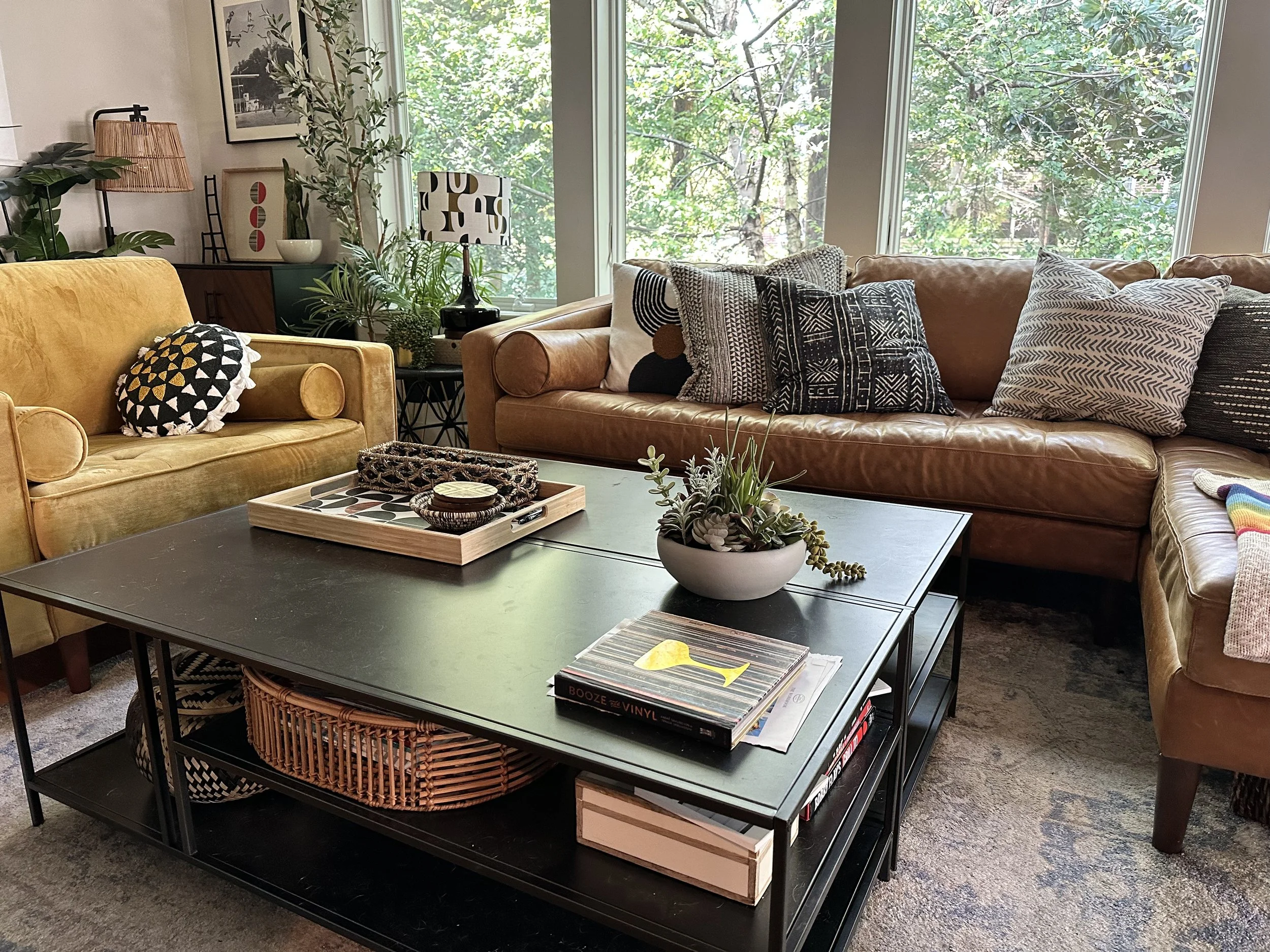 AFTER: a warm cognac leather couch from Poly+Bark pairs well with the greenery outside the window, and the large black coffee table grounds everything