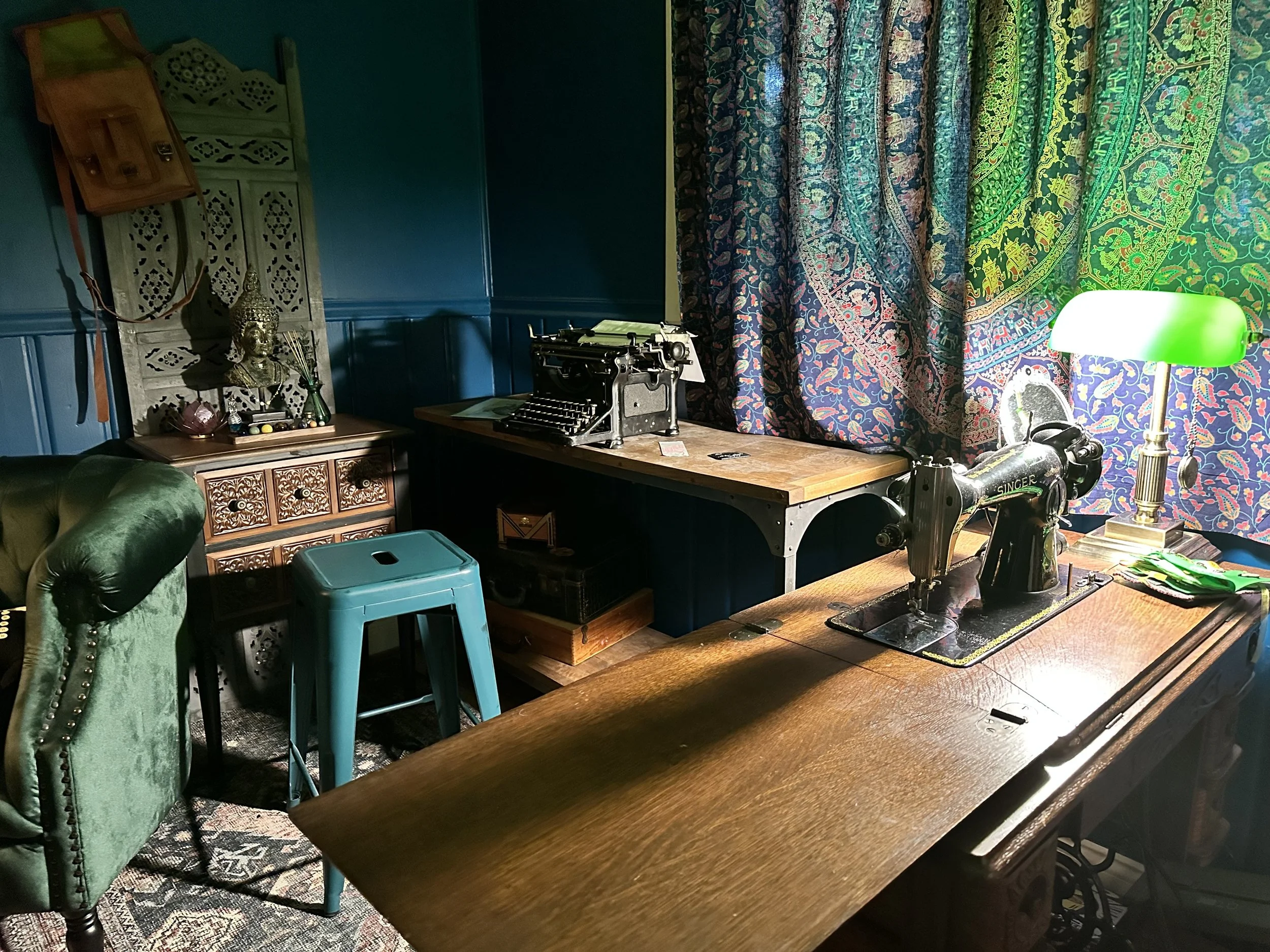 AFTER: a batik wall hanging cut in half became the curtains for this room, with an antique banker's lamp, antique sewing machine, and antique typewriter having pride of place. 