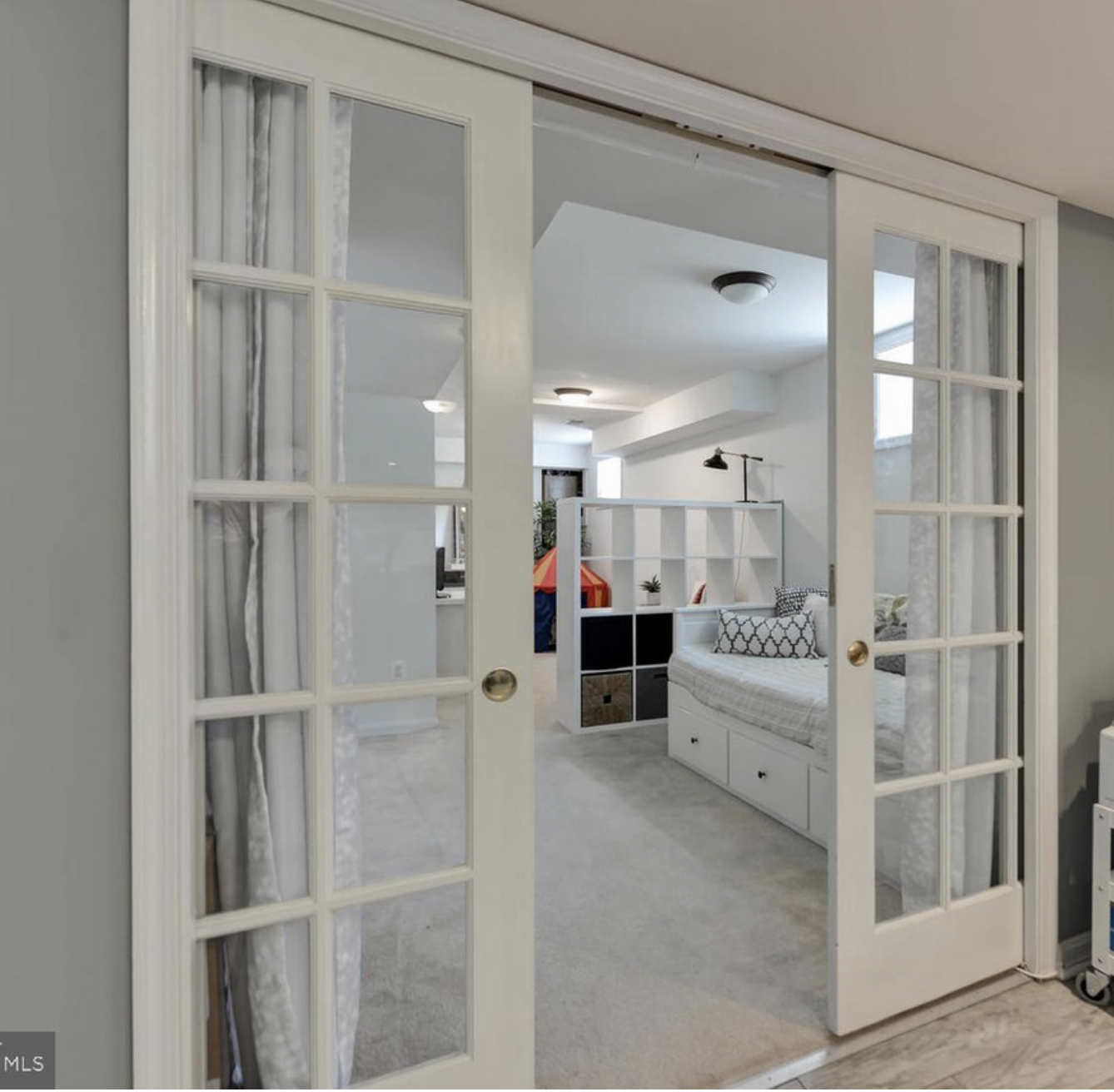 AFTER: A nice coat of white paint, a daybed with pullout storage, curtains on the pocket doors for privacy, and a shelving unit to separate the little sitting area and kitchen from the bedroom, and bam, you've got yourself a lovely, welcoming guest r