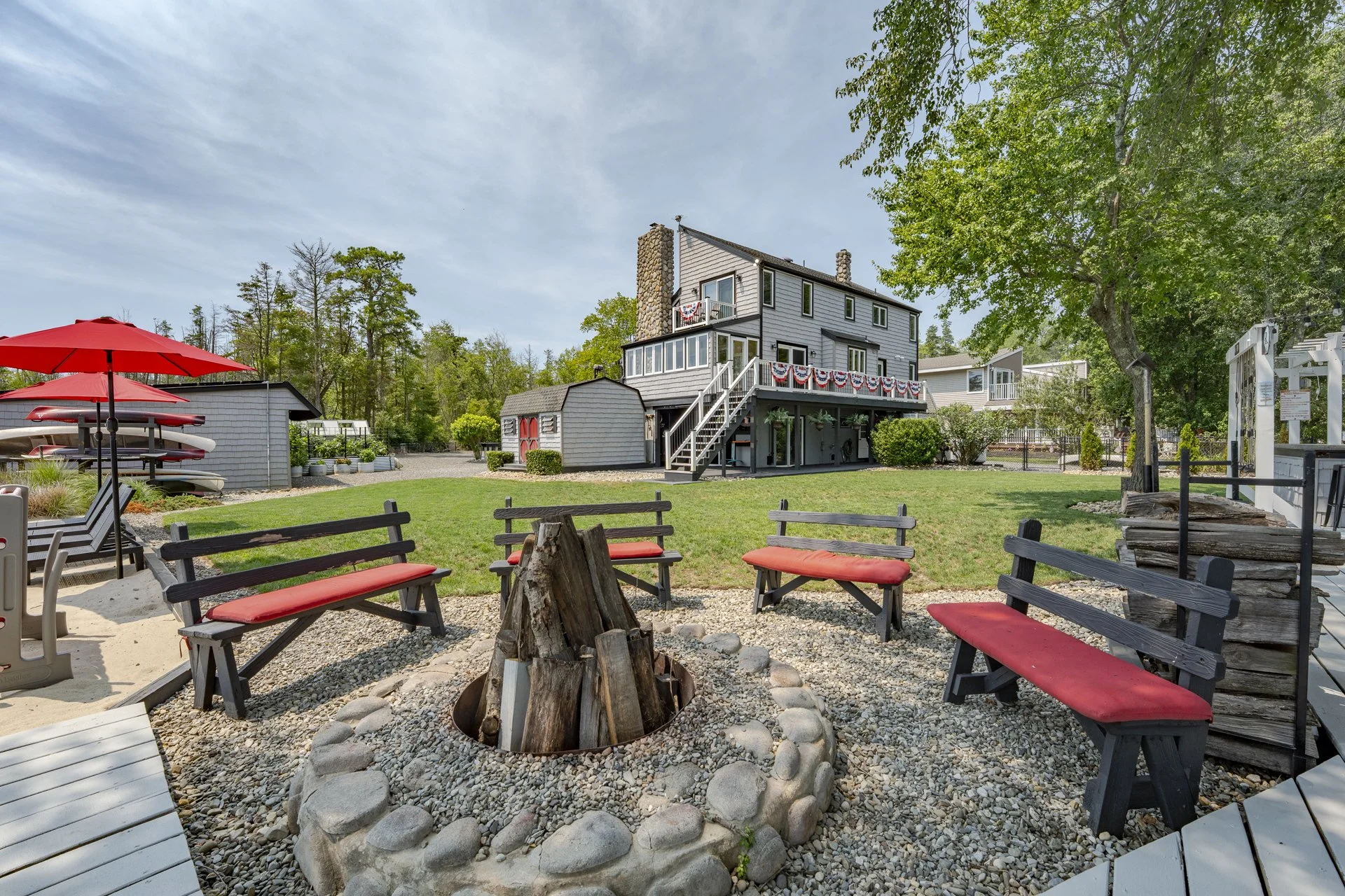 Waterfront entertaining features a private sandy beach, fire pit, and custom outdoor kitchen.