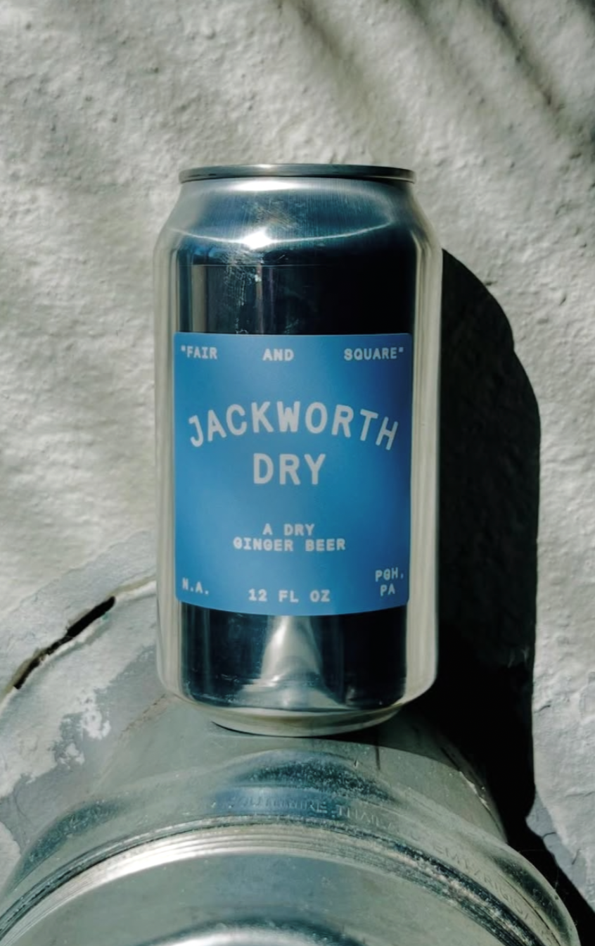 Can of Jackworth Dry Ginger Beer on a metal surface with a textured white wall in the background.