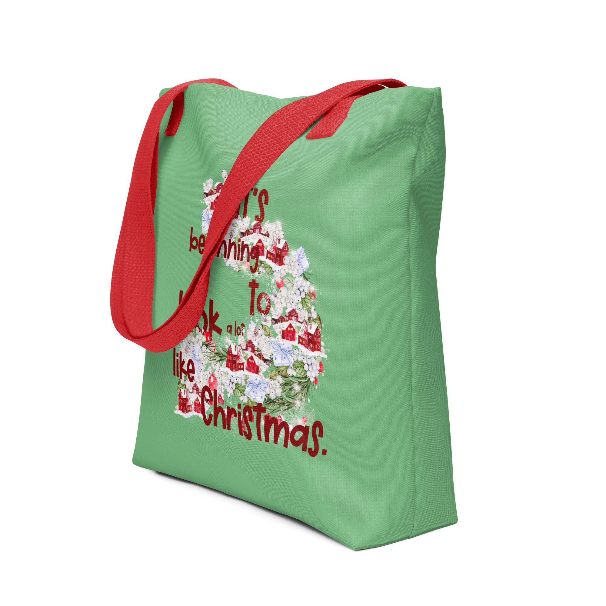 Profile image of a green tote bag with a red handle that has a festive design and the words It's beginning to look a lot like Christmas.