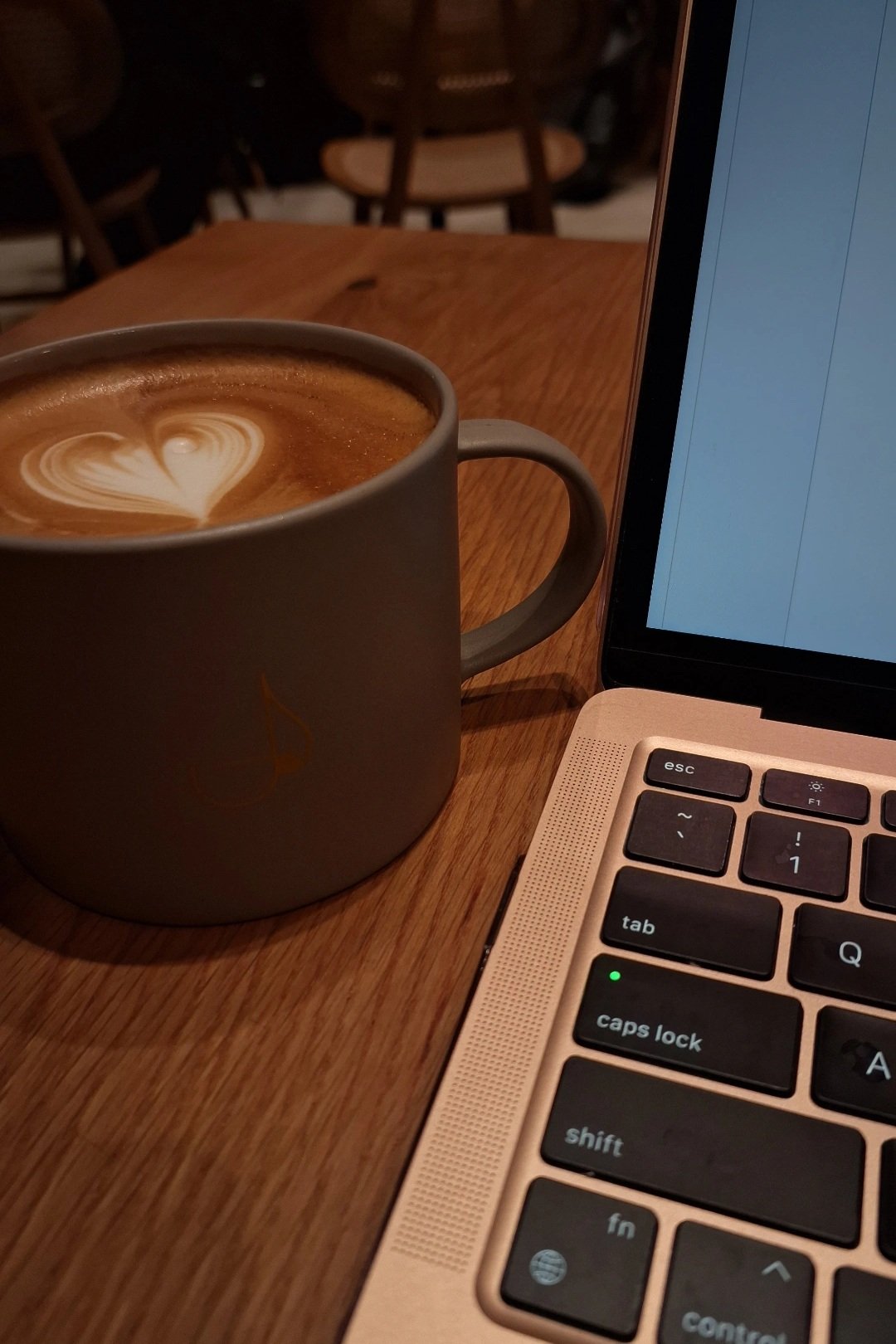 Laptop keyboard and coffee cup with latte art on wooden table