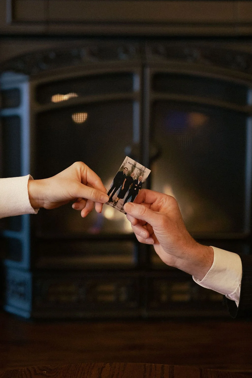 Two people exchanging a business card with a fireplace in the background
