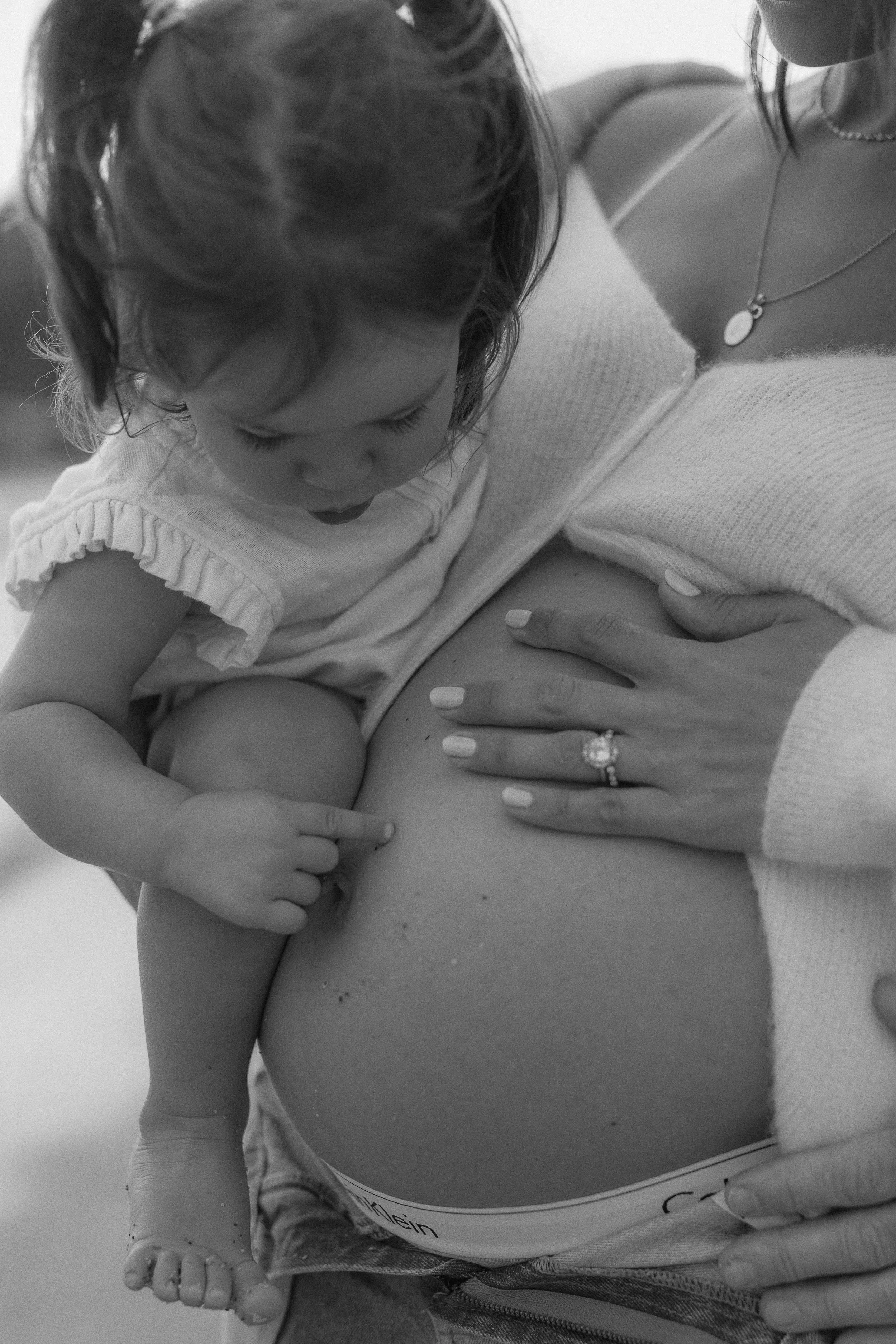 A young child breastfeeding while holding hands with an adult, showing close-up of their faces and interaction.