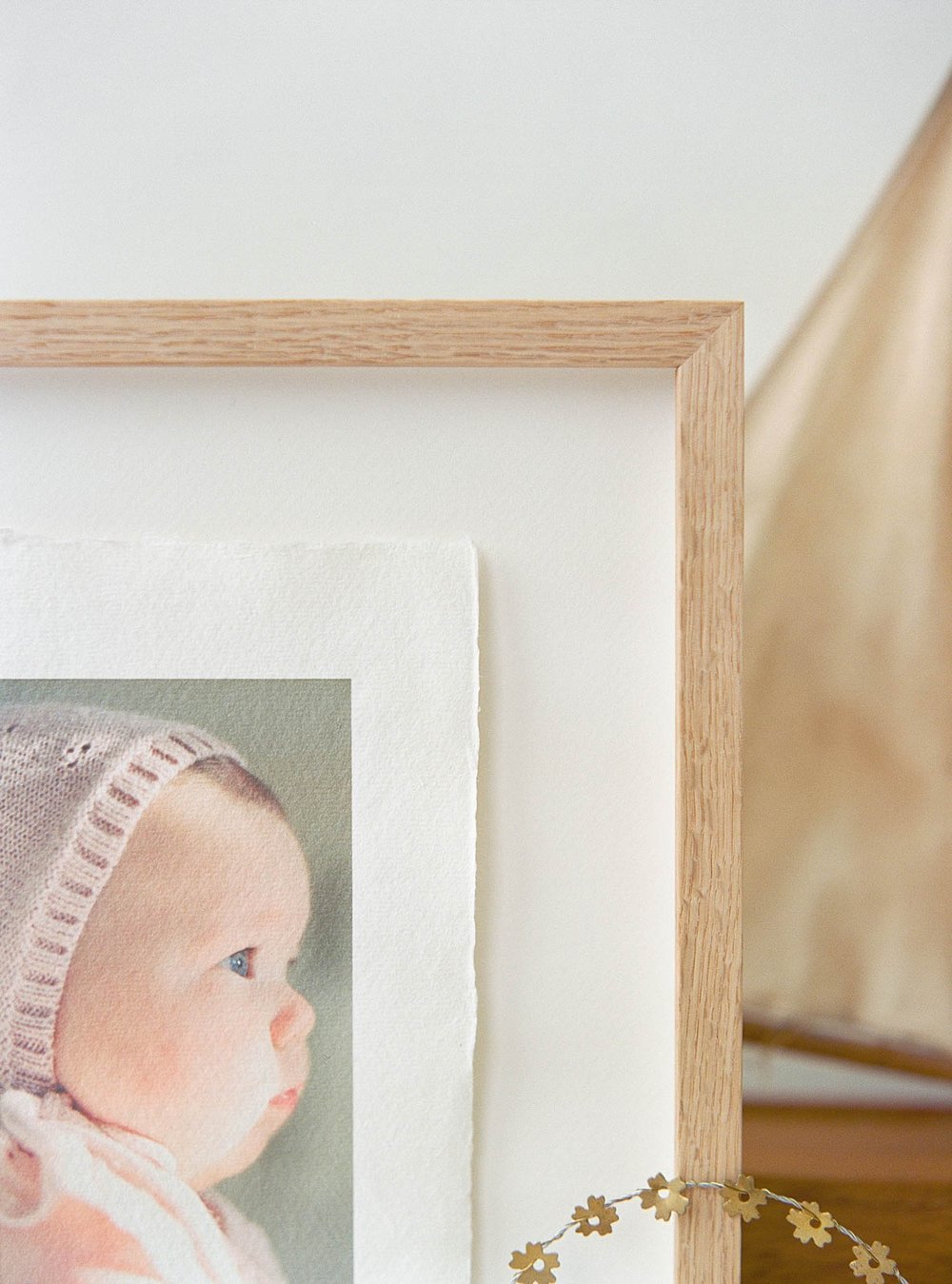 Close-up of a framed photograph featuring a baby in a knit hat, with a wooden boat-like structure in the background.
