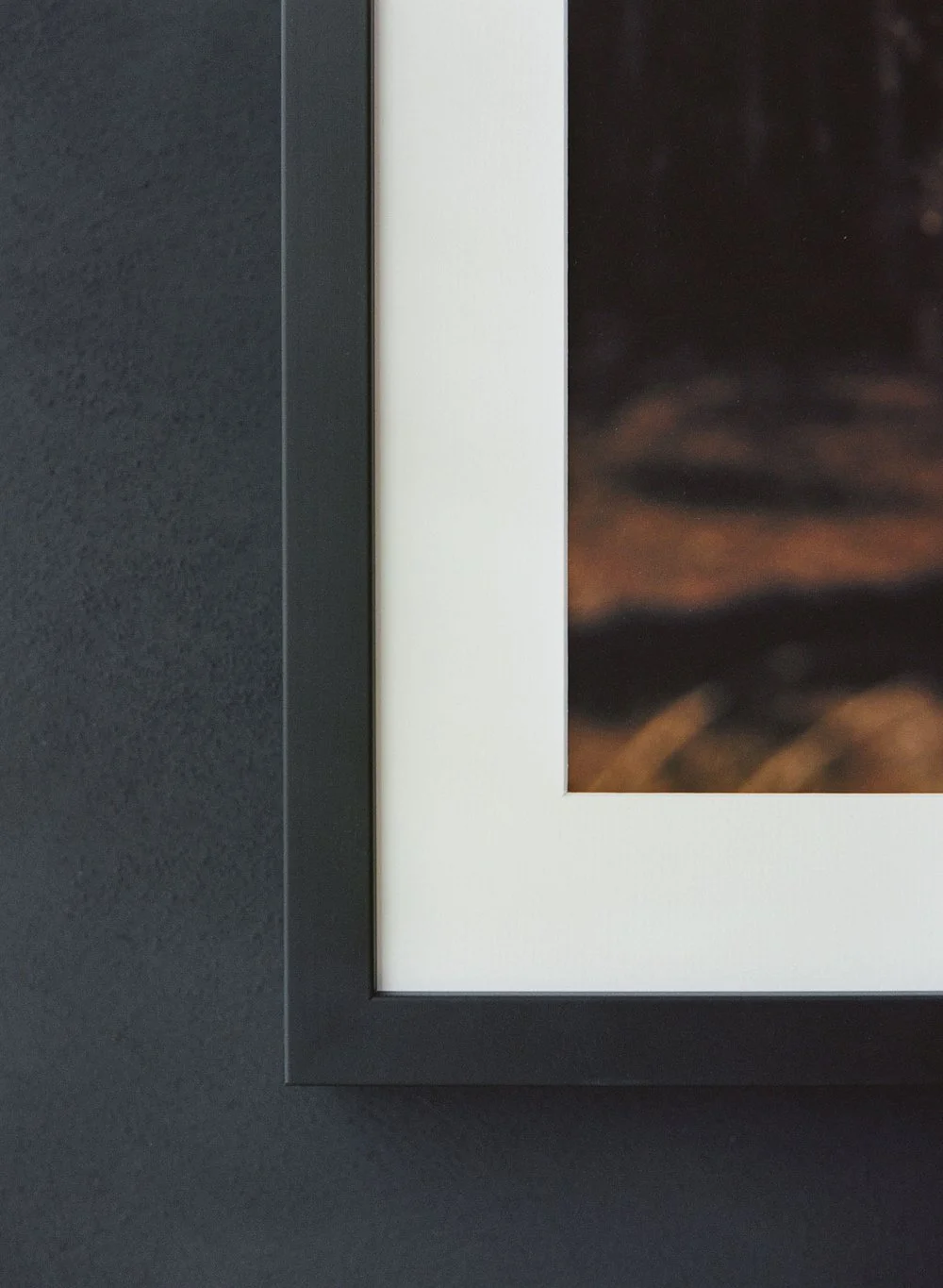 Black picture frame corner on dark wall with image inset.