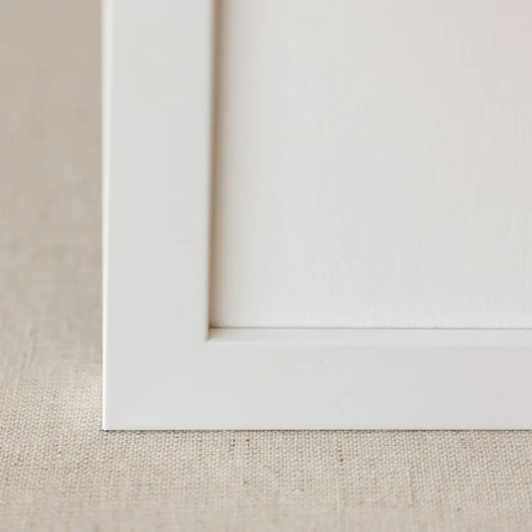 Close-up of a white picture frame corner on textured beige background