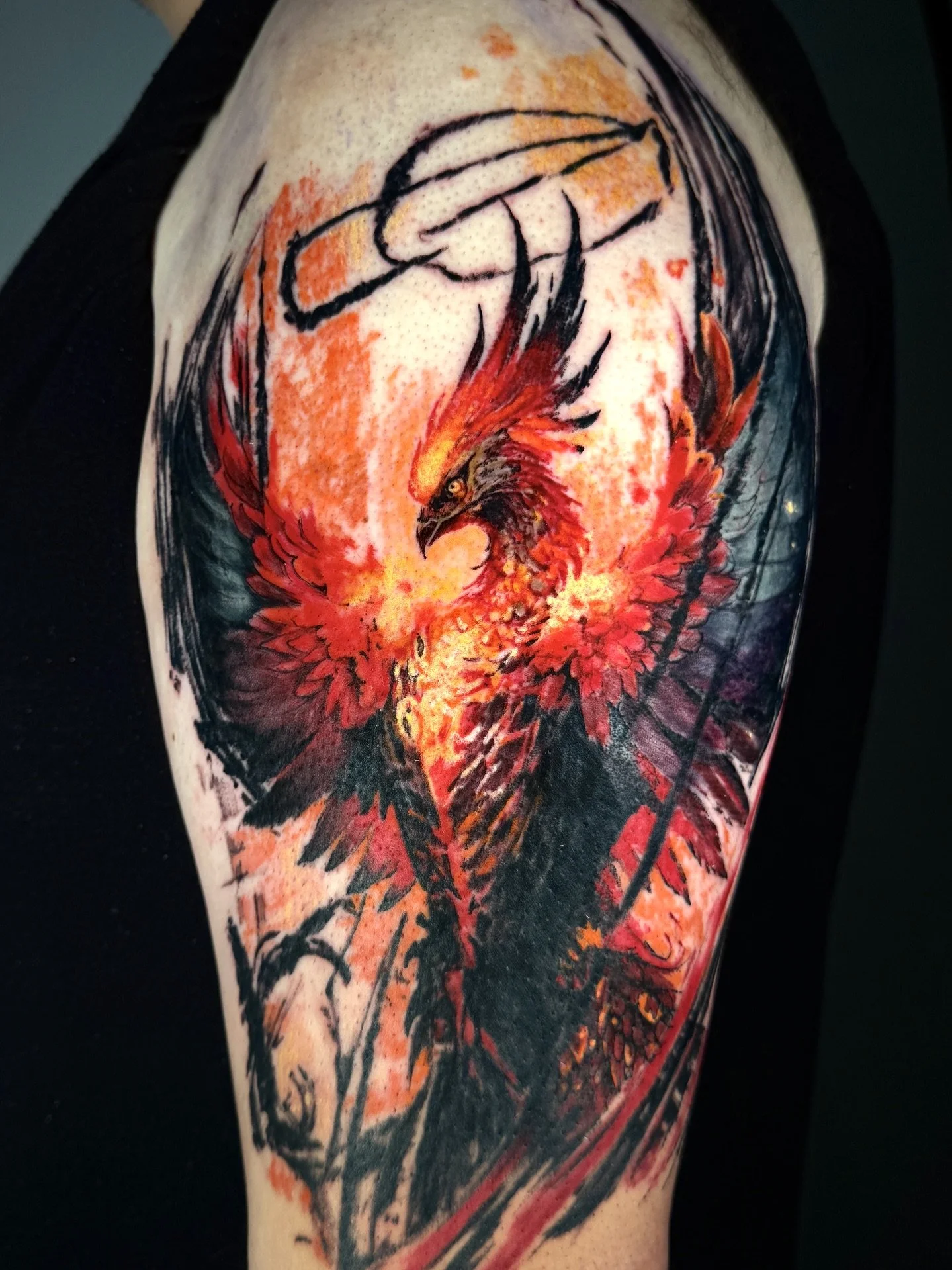 Tattoo of a fierce phoenix with black, red, and orange flames on a person's arm.