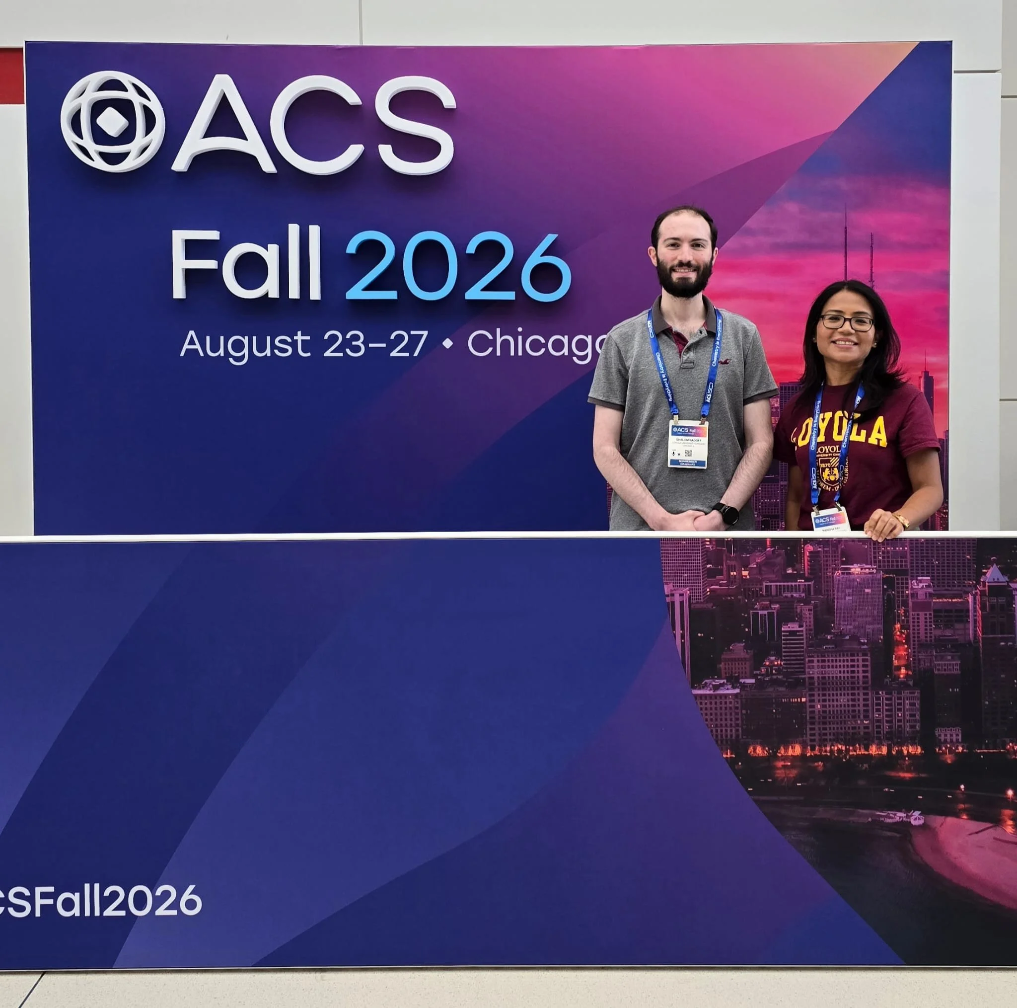 Shalom and Manisha in front of ACS logo