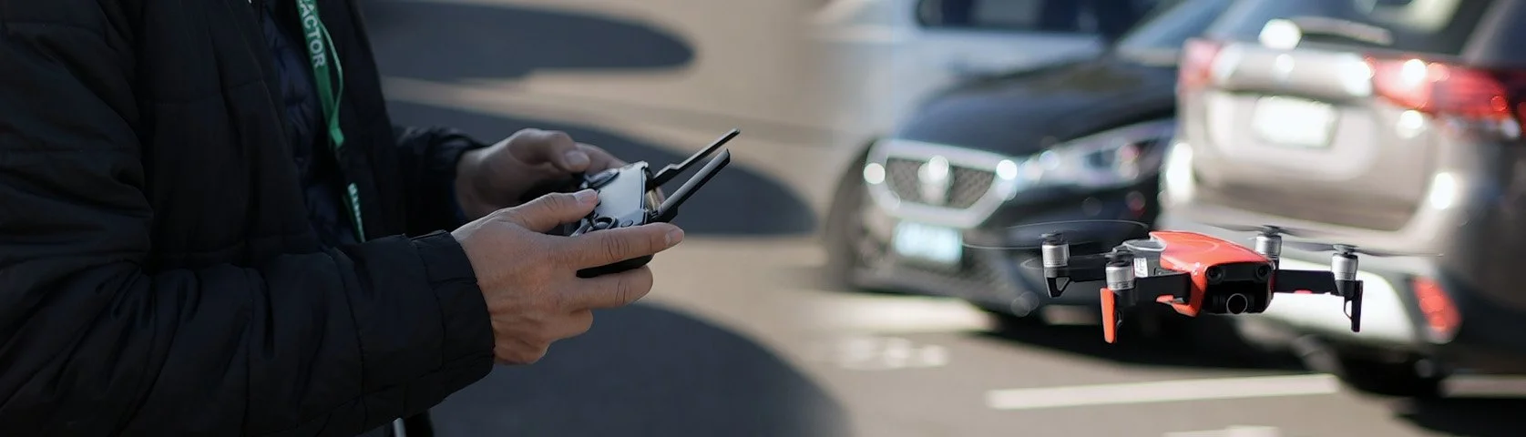 Person operating a drone using a remote control in a parking lot.