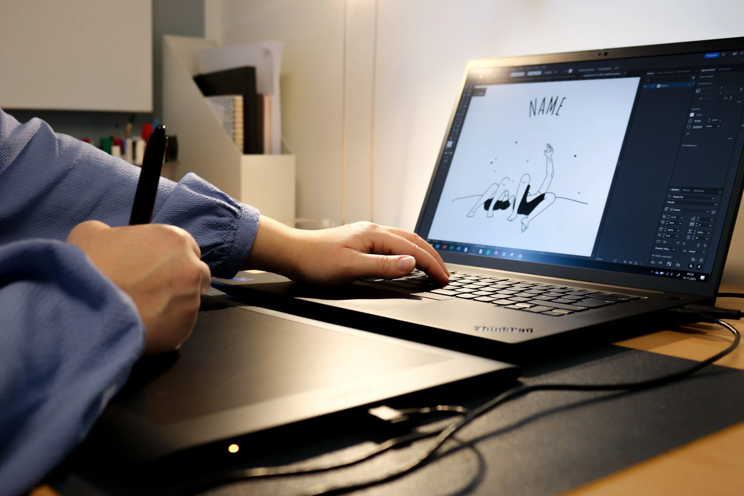 Person arbeitet an einem Laptop und zeichnet eine Illustration auf dem Bildschirm, mit einem Zeichenstift in der Hand.