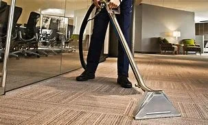 Person vacuuming a carpeted floor in an office setting