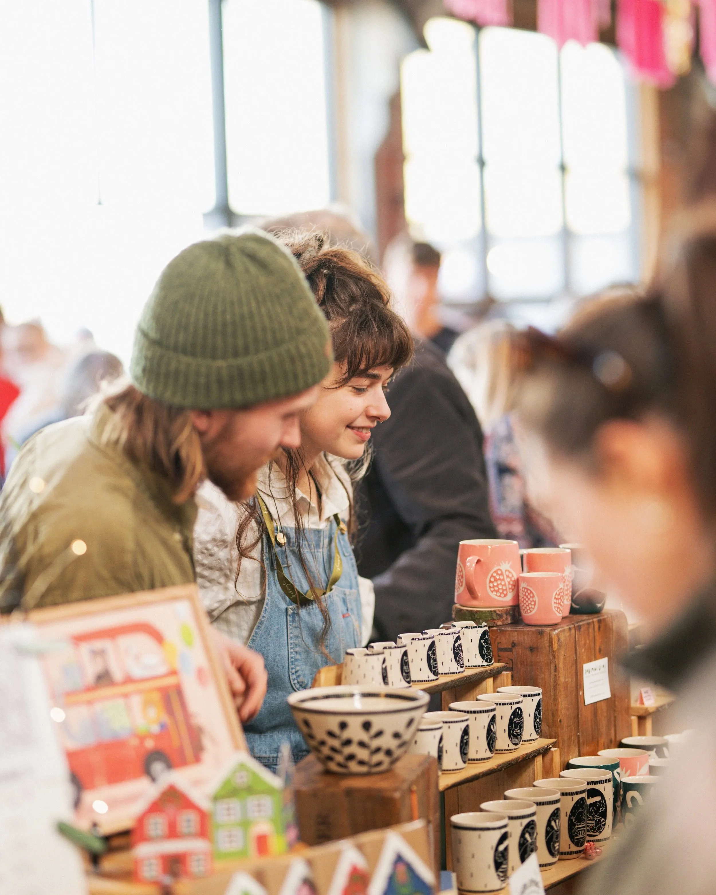 Crowded indoor market scene with people and hanging decorations.