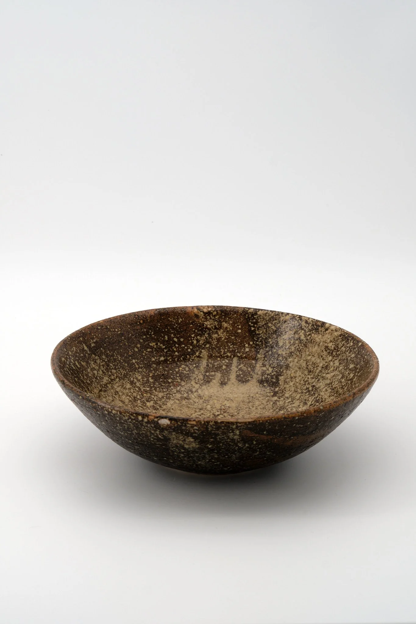 A speckled brown ceramic bowl on a white background.