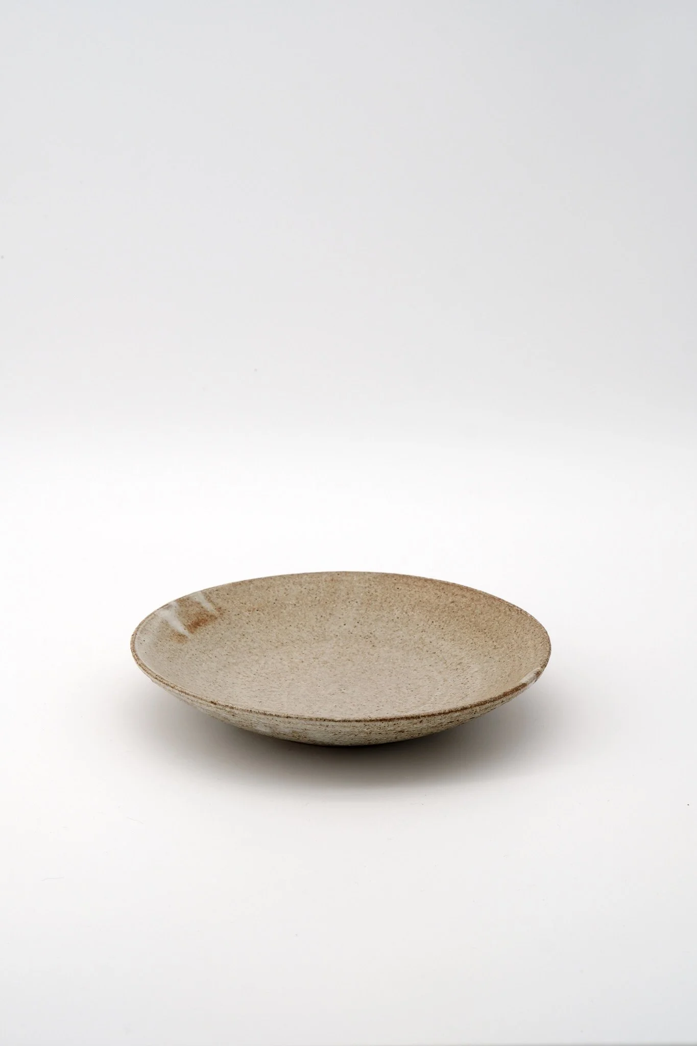 A ceramic bowl with a rustic, speckled finish on a white background.