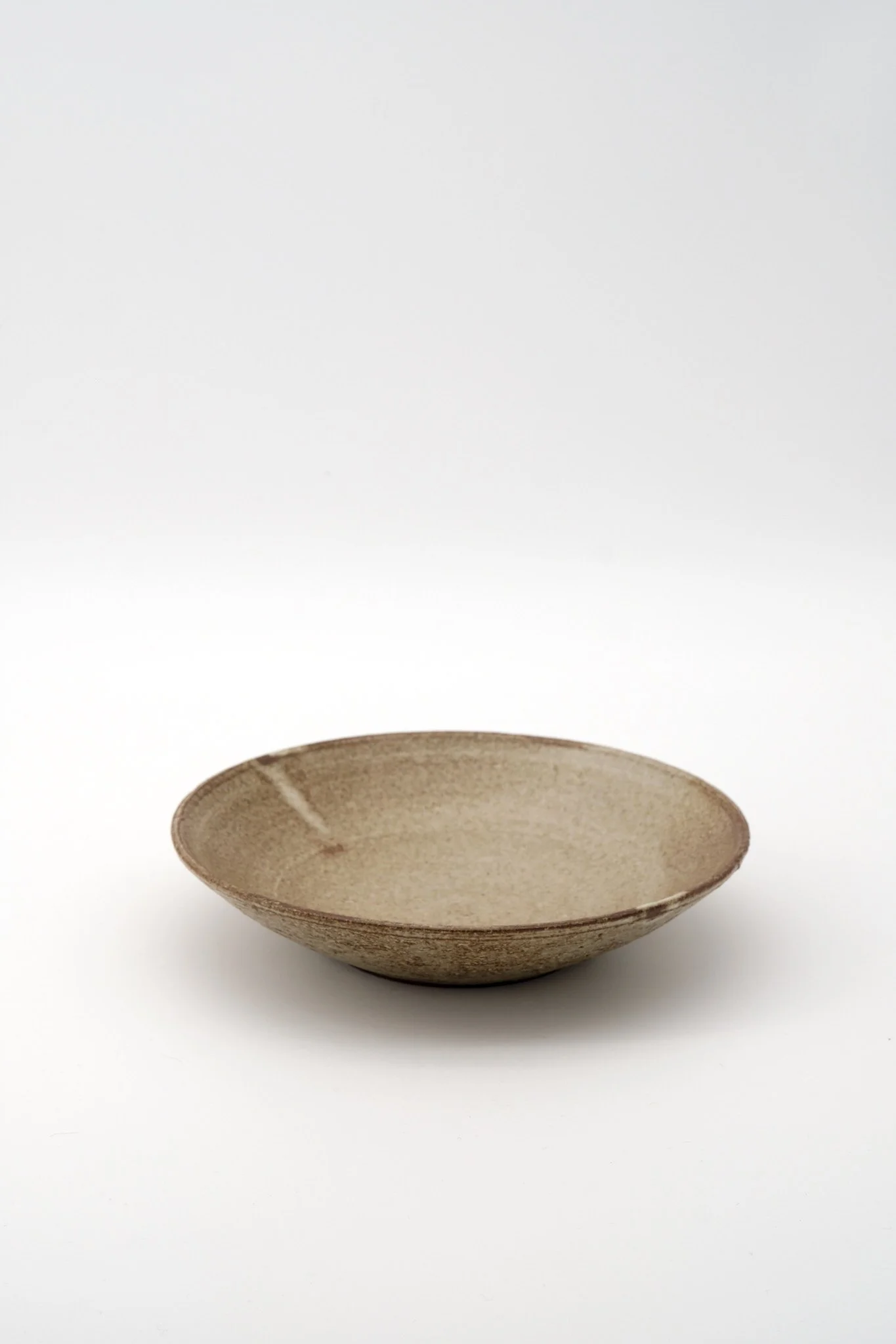 A beige ceramic bowl with a textured surface on a white background.