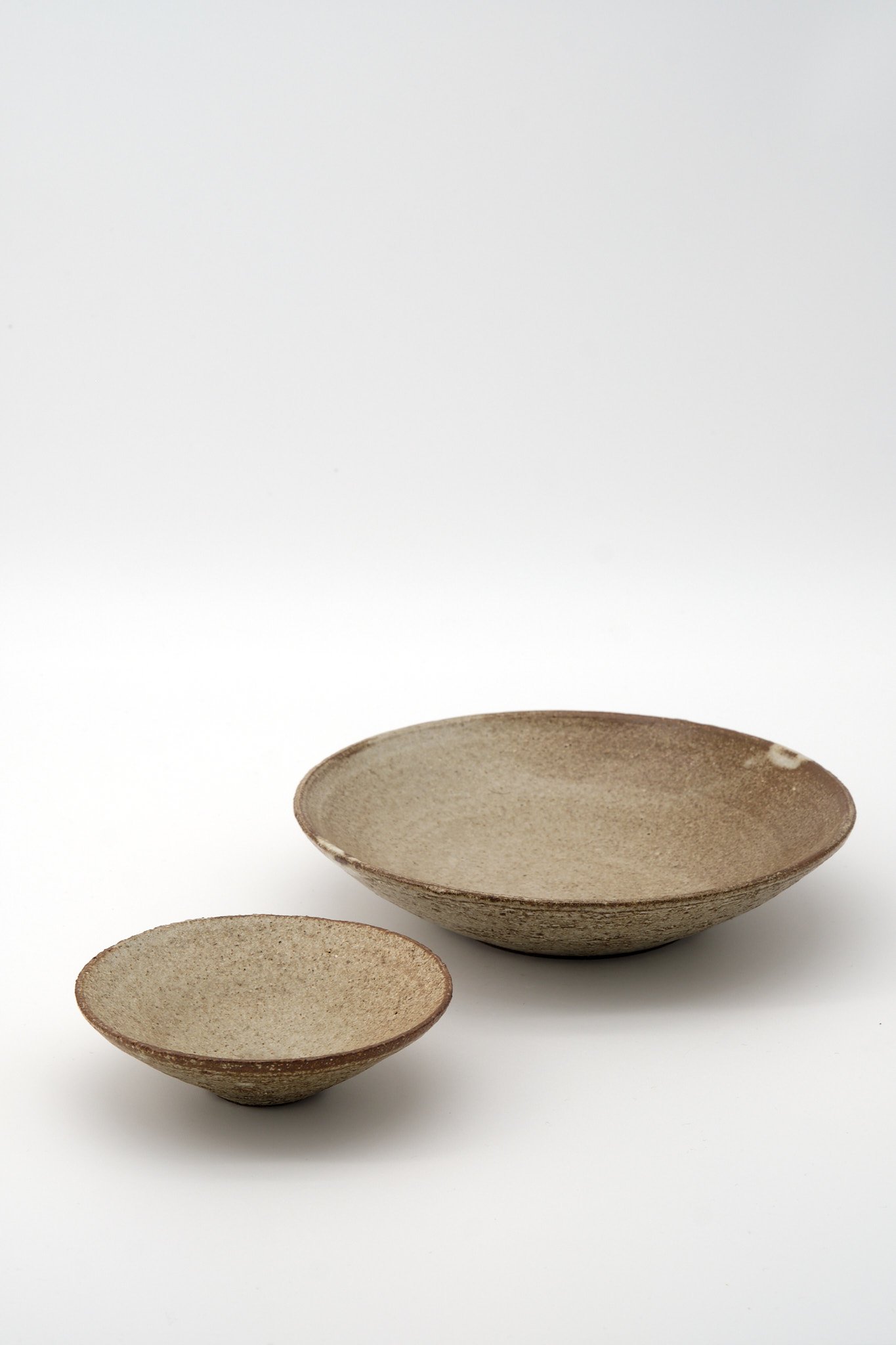 Three empty ceramic bowls in varying sizes, placed on a white surface against a plain background.