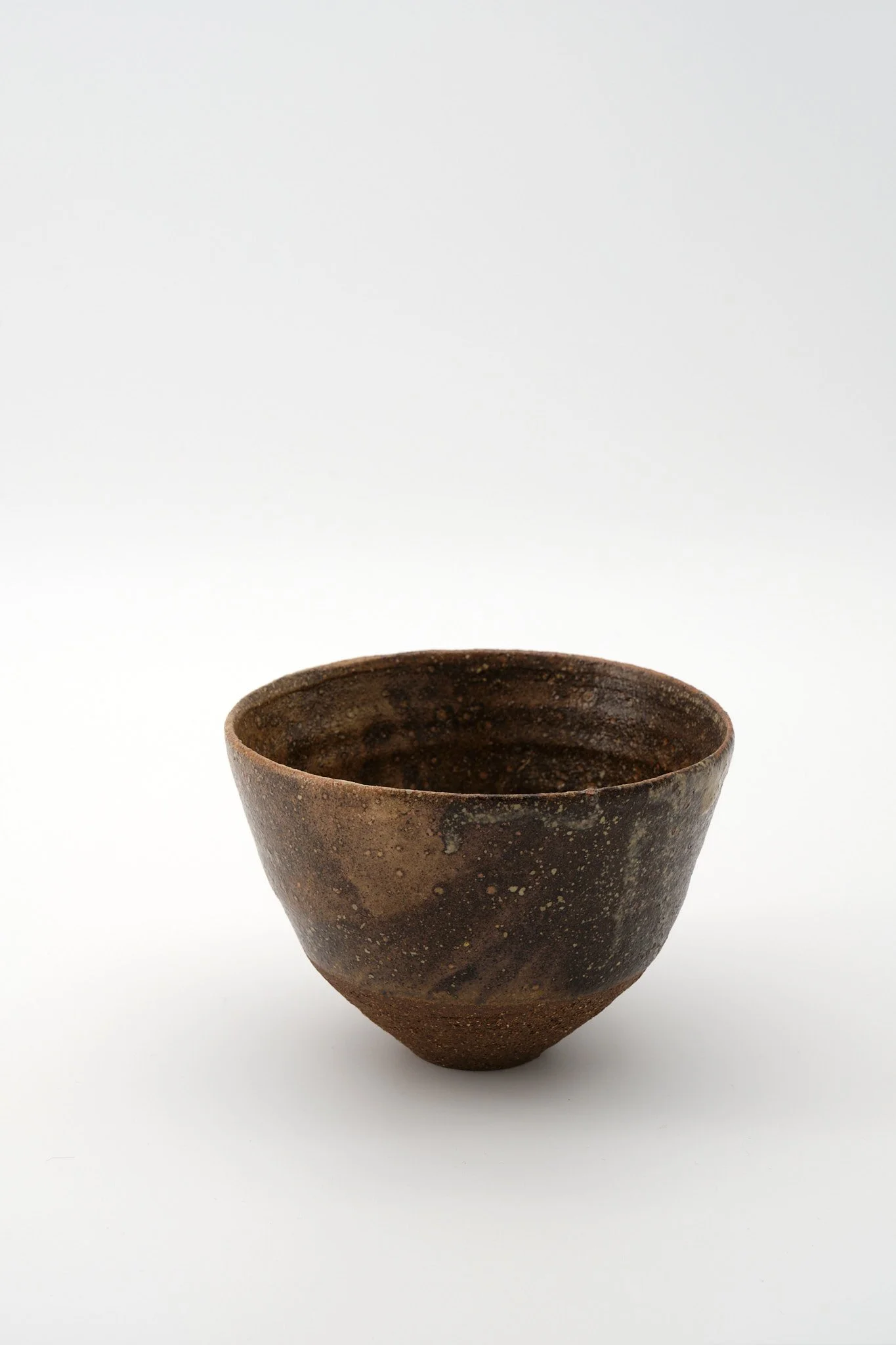 An old, dark brown textured ceramic pot on a white background.