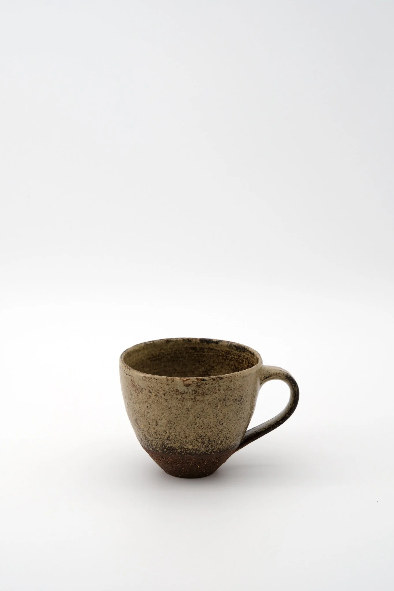 Brown ceramic mug with a rustic, textured surface against a plain white background.