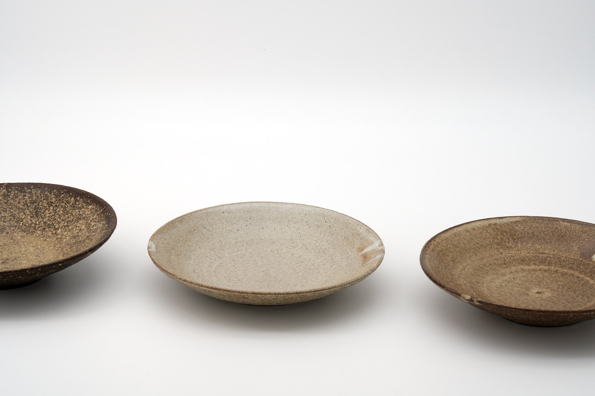 Three ceramic bowls with different textures and colors placed on a white background.